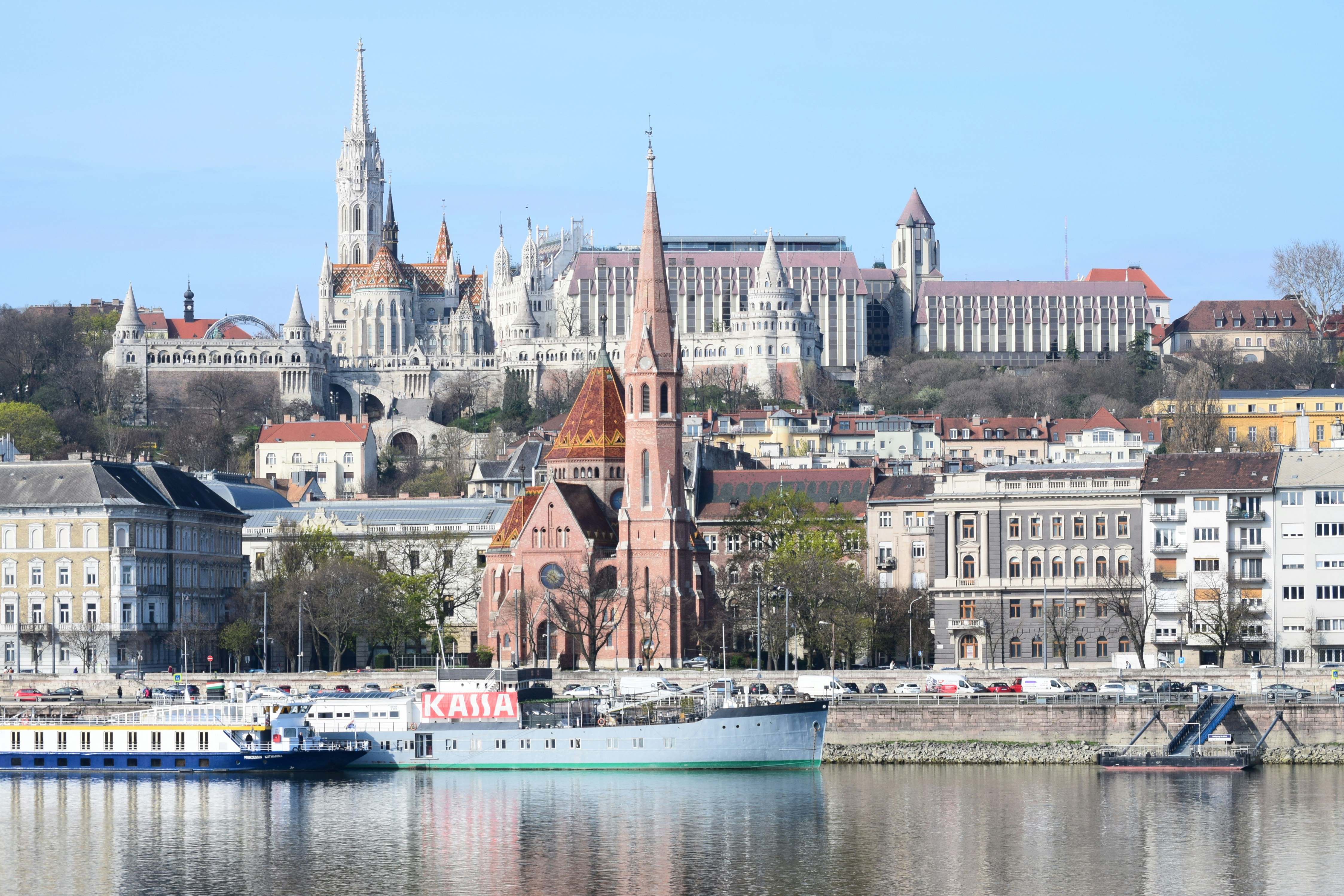 Cityscape with historic buildings and a riverboat.
