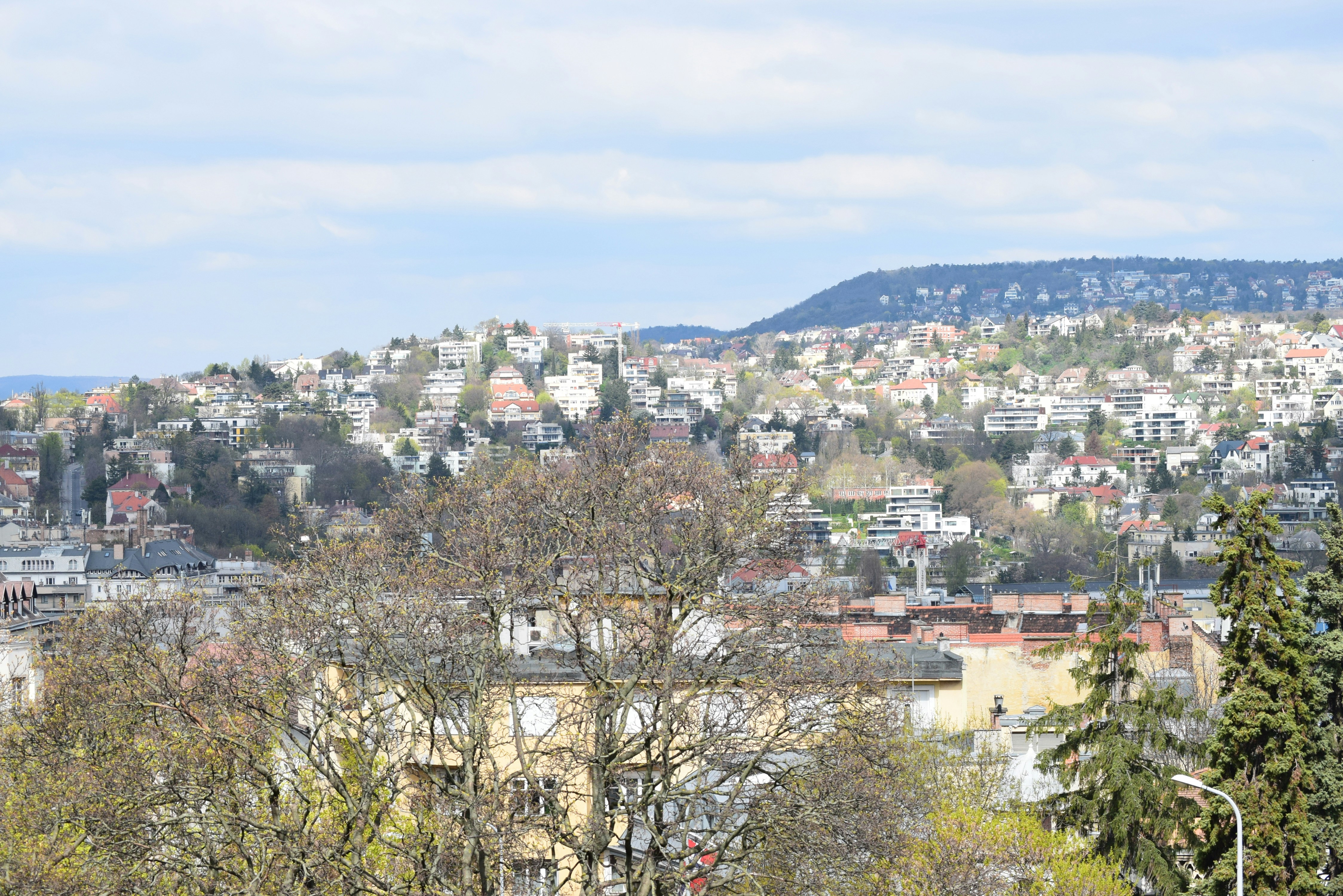 A sprawling city with rolling hills under a cloudy sky.