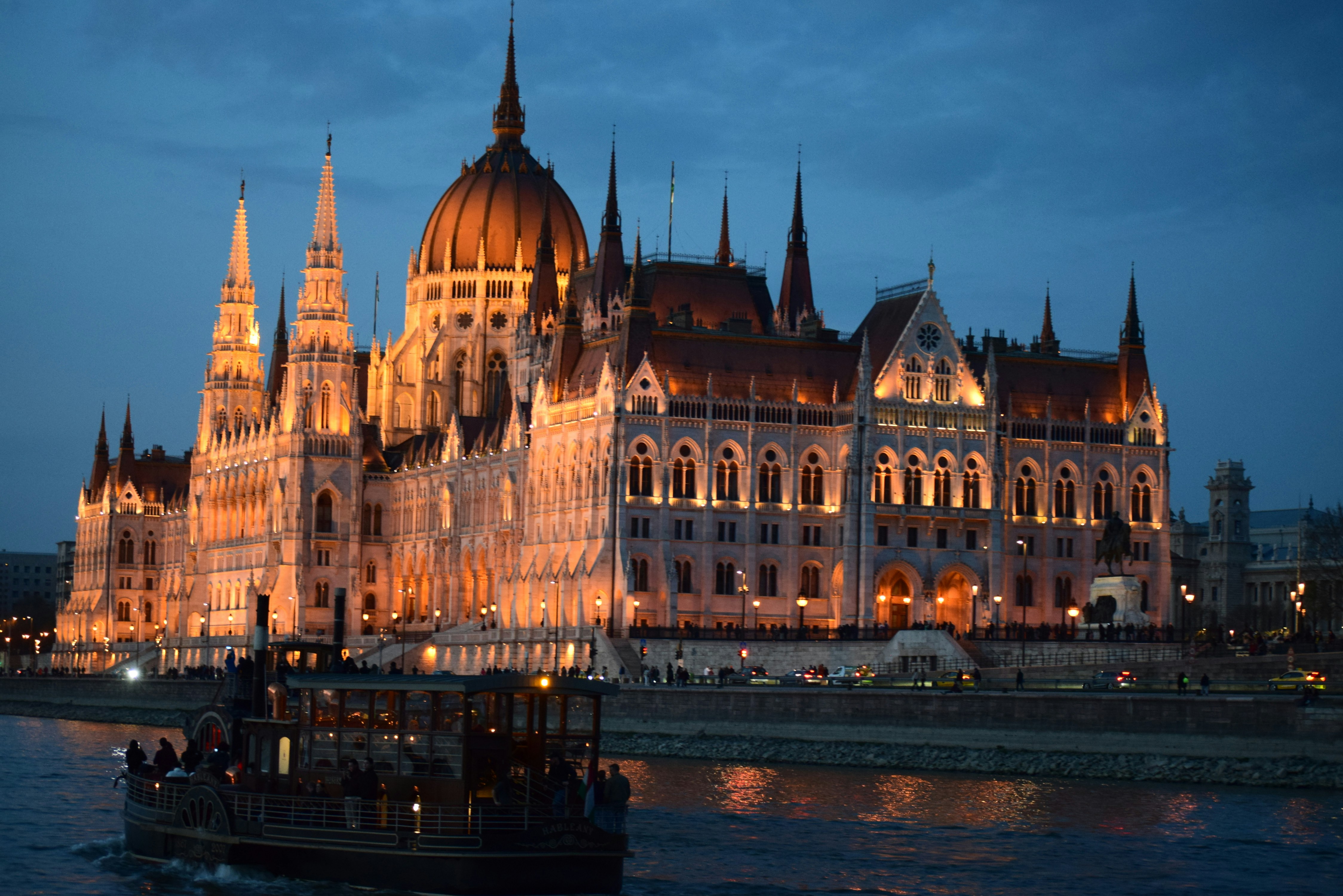 Illuminated parliament building on river at dusk