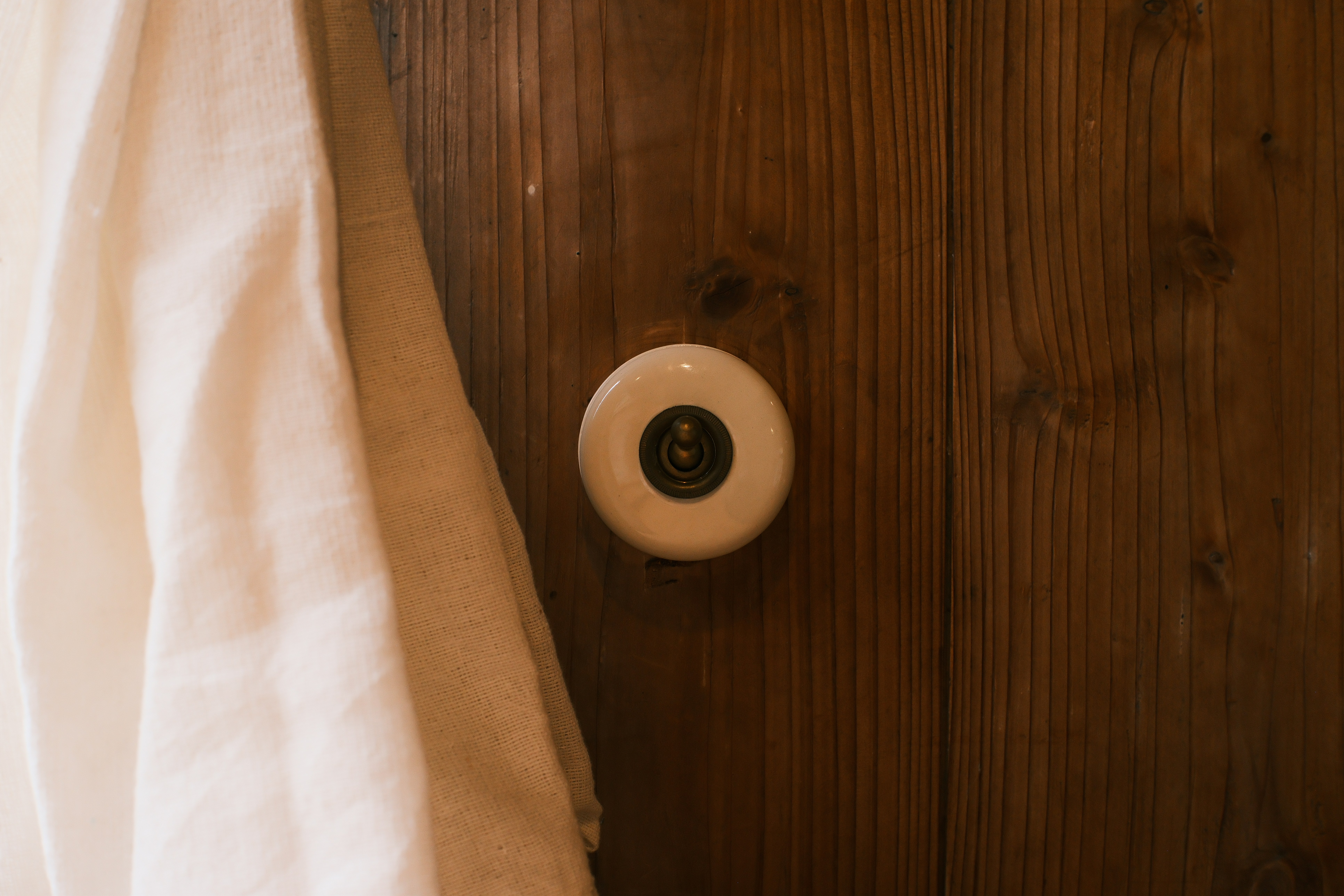 Nahaufnahme eines weißen Keramik-Türknaufs an einer Holztür