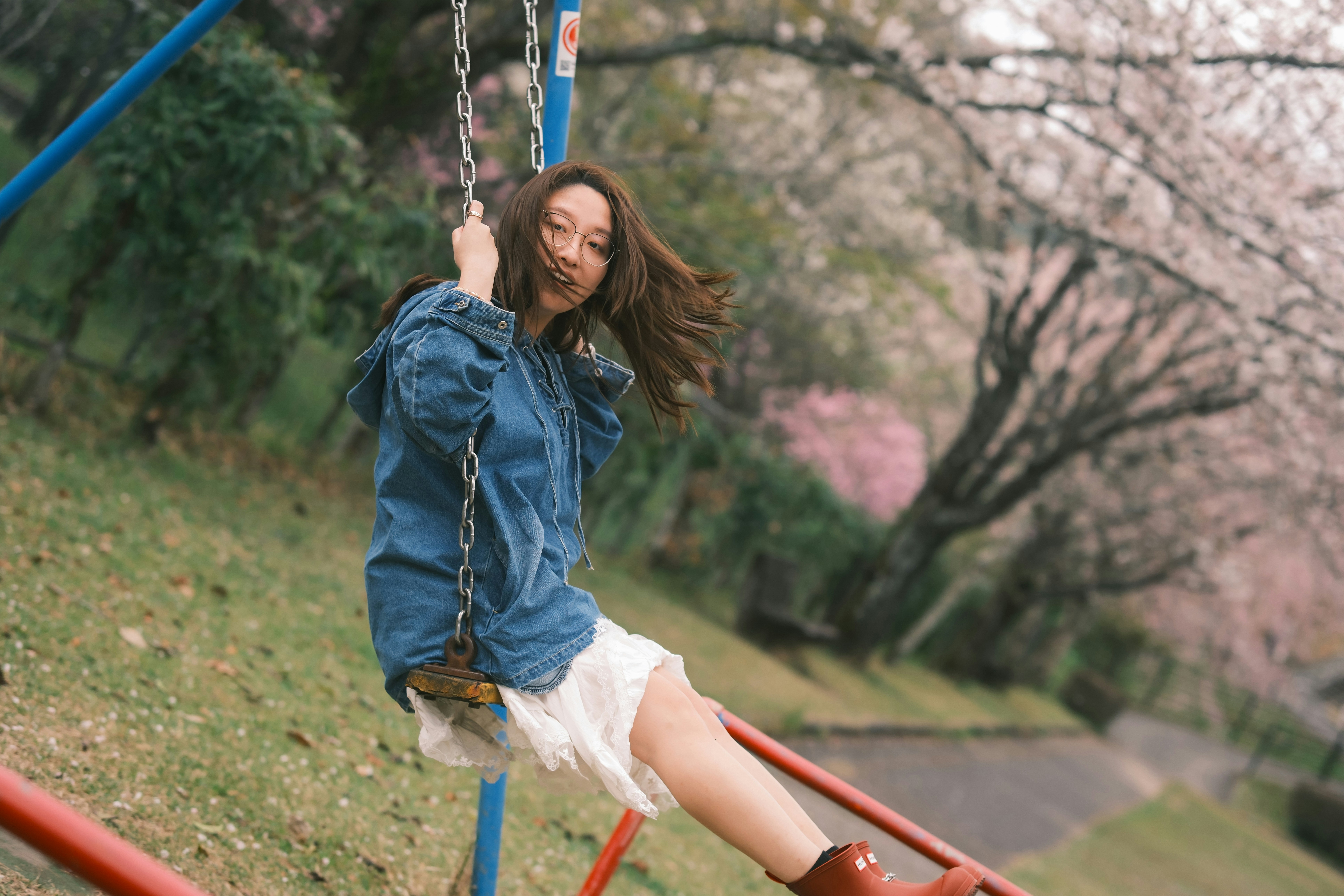 Young woman swinging on a swing set in park.