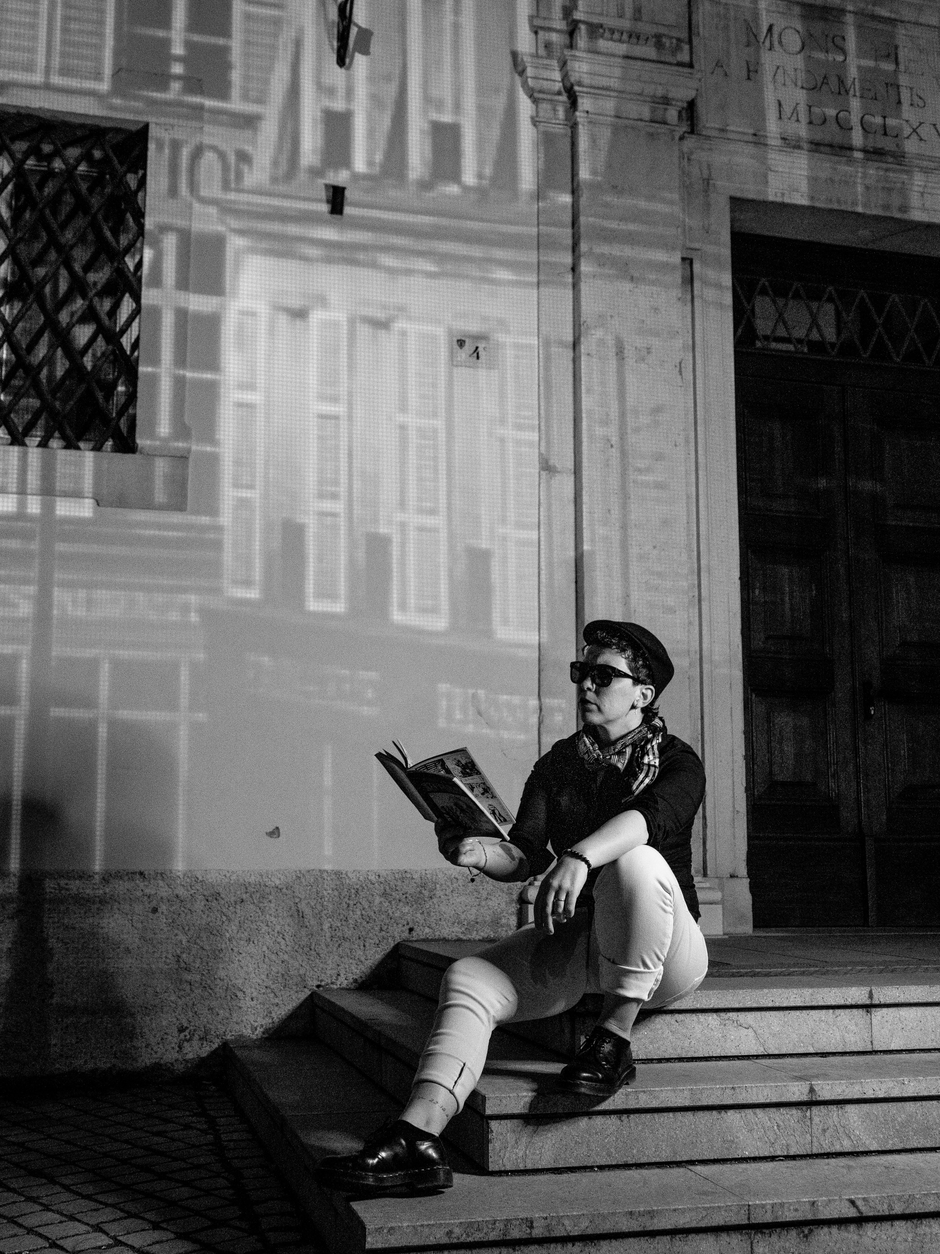 Persona che legge un libro sui gradini di notte.