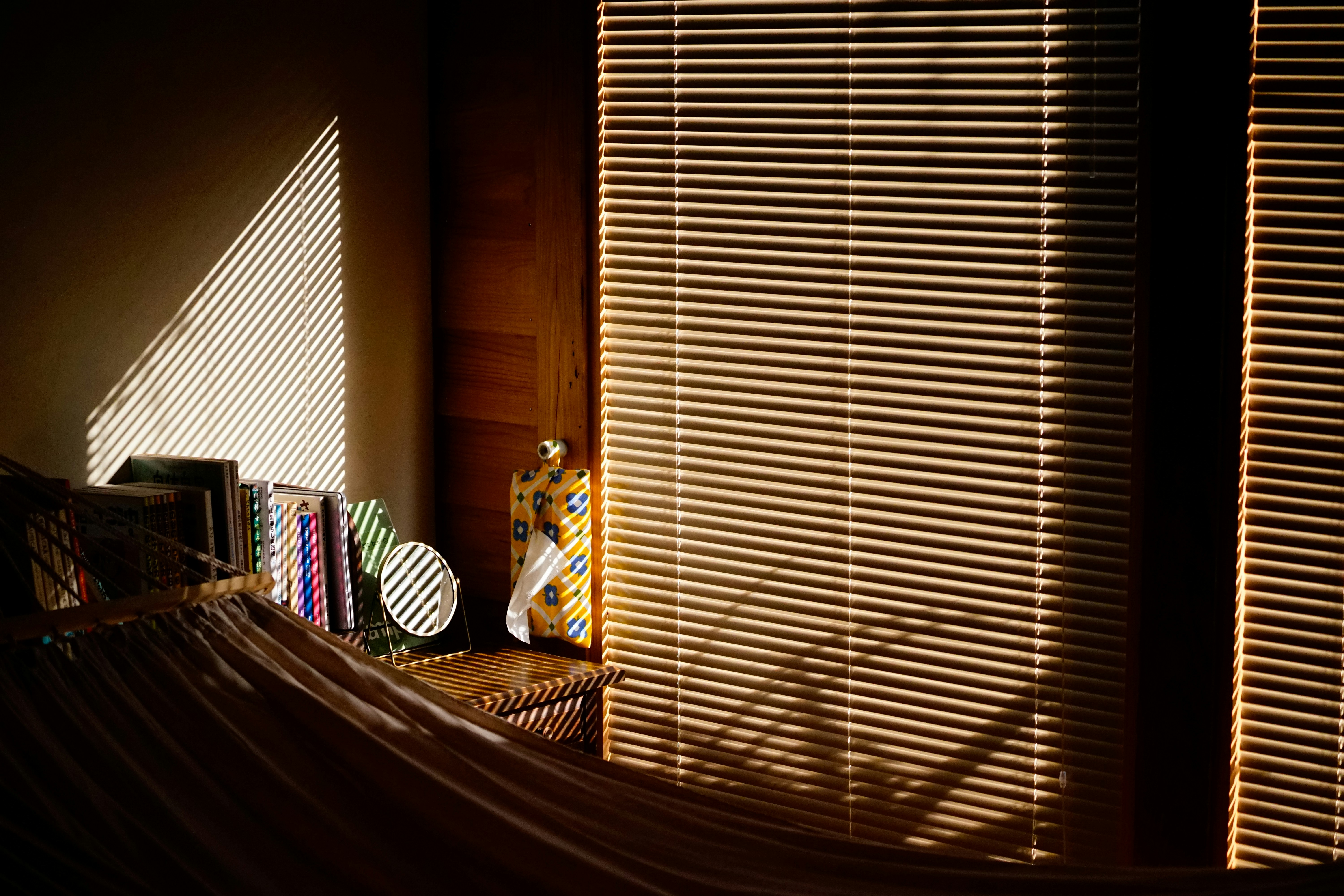 Sunlight streams through blinds onto a shelf.
