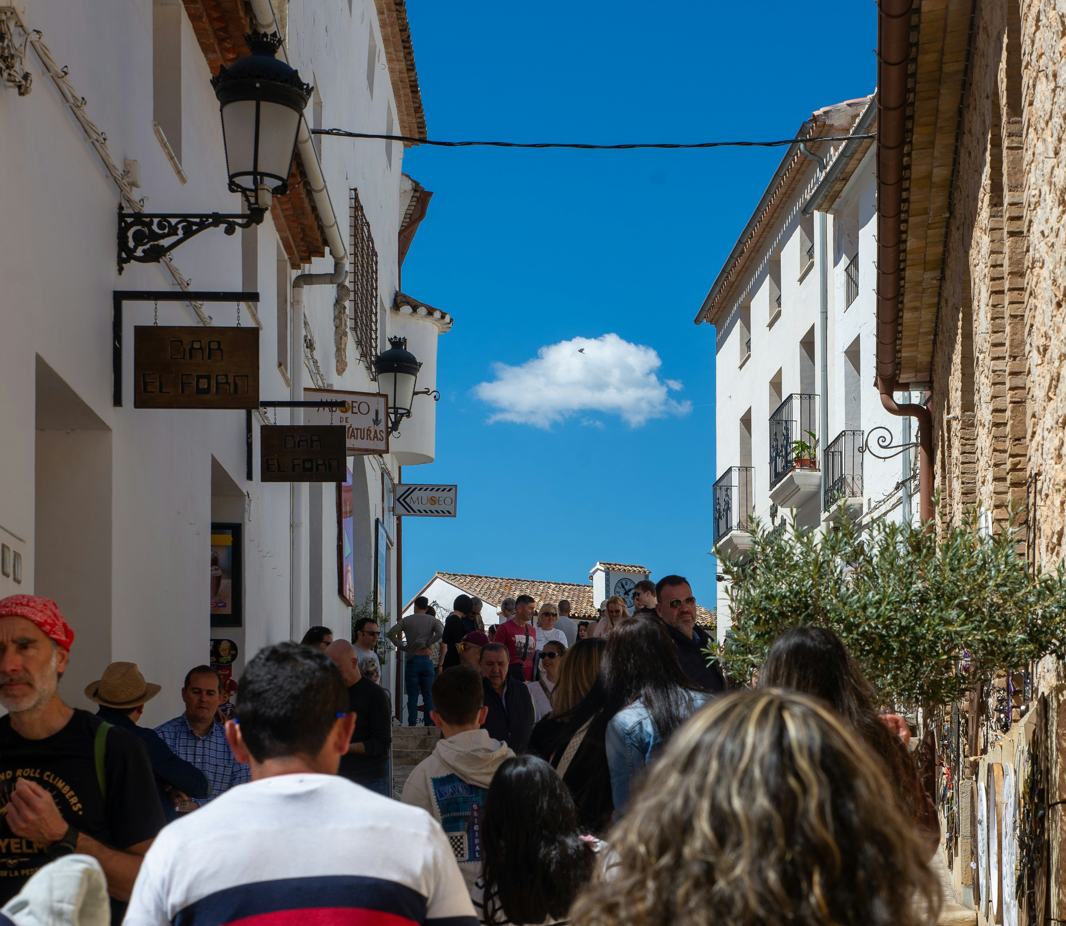 People walking down a narrow street with buildings.