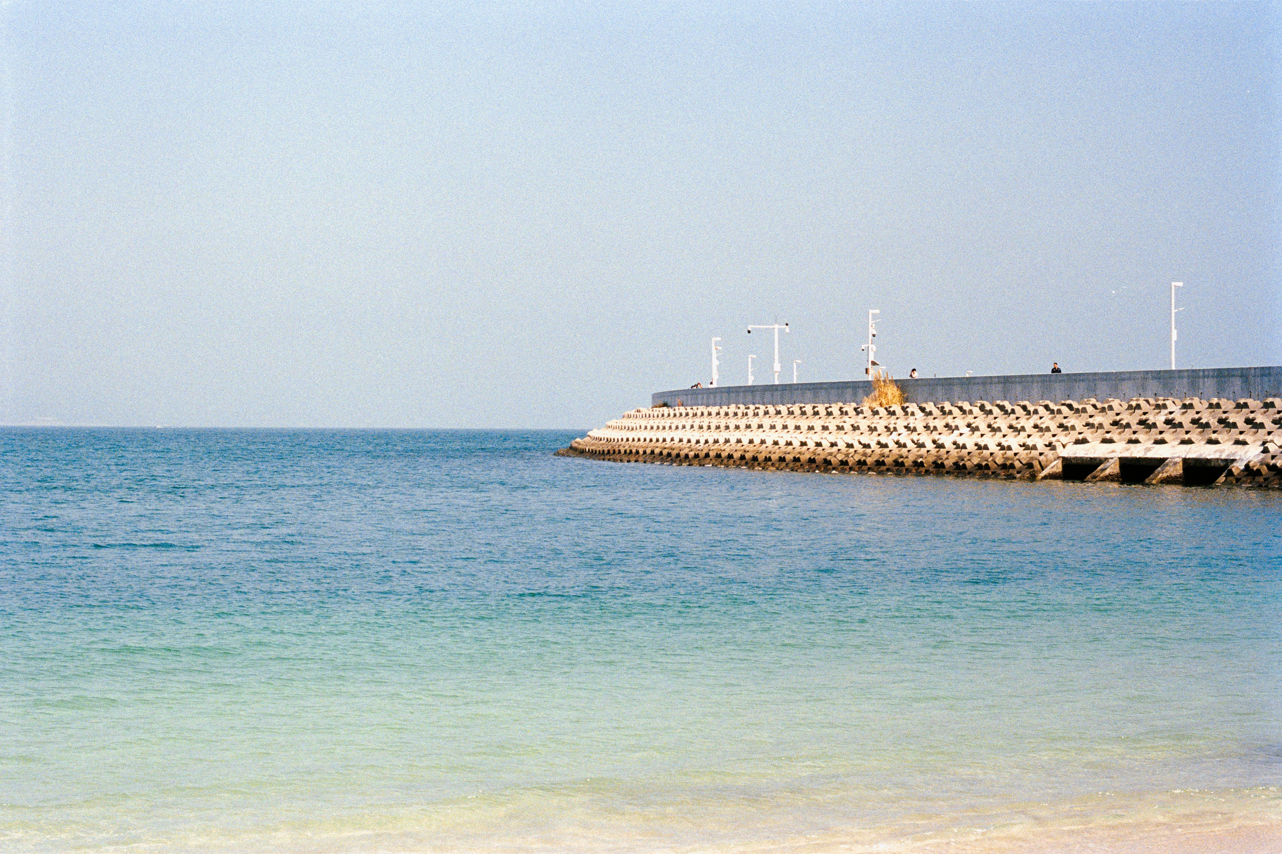 Concrete breakwater extending into the calm blue ocean