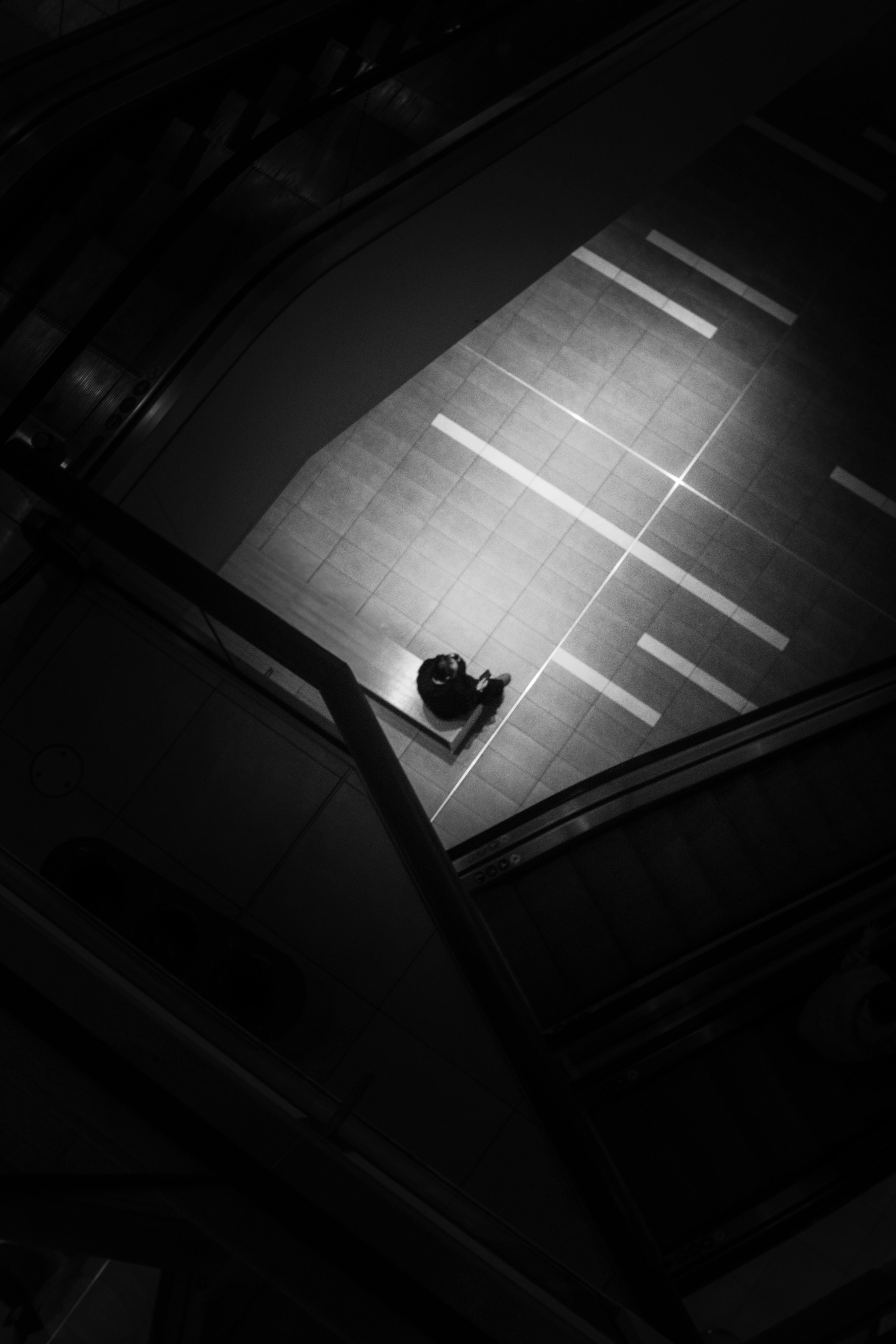 A lone figure stands on a brightly lit floor.