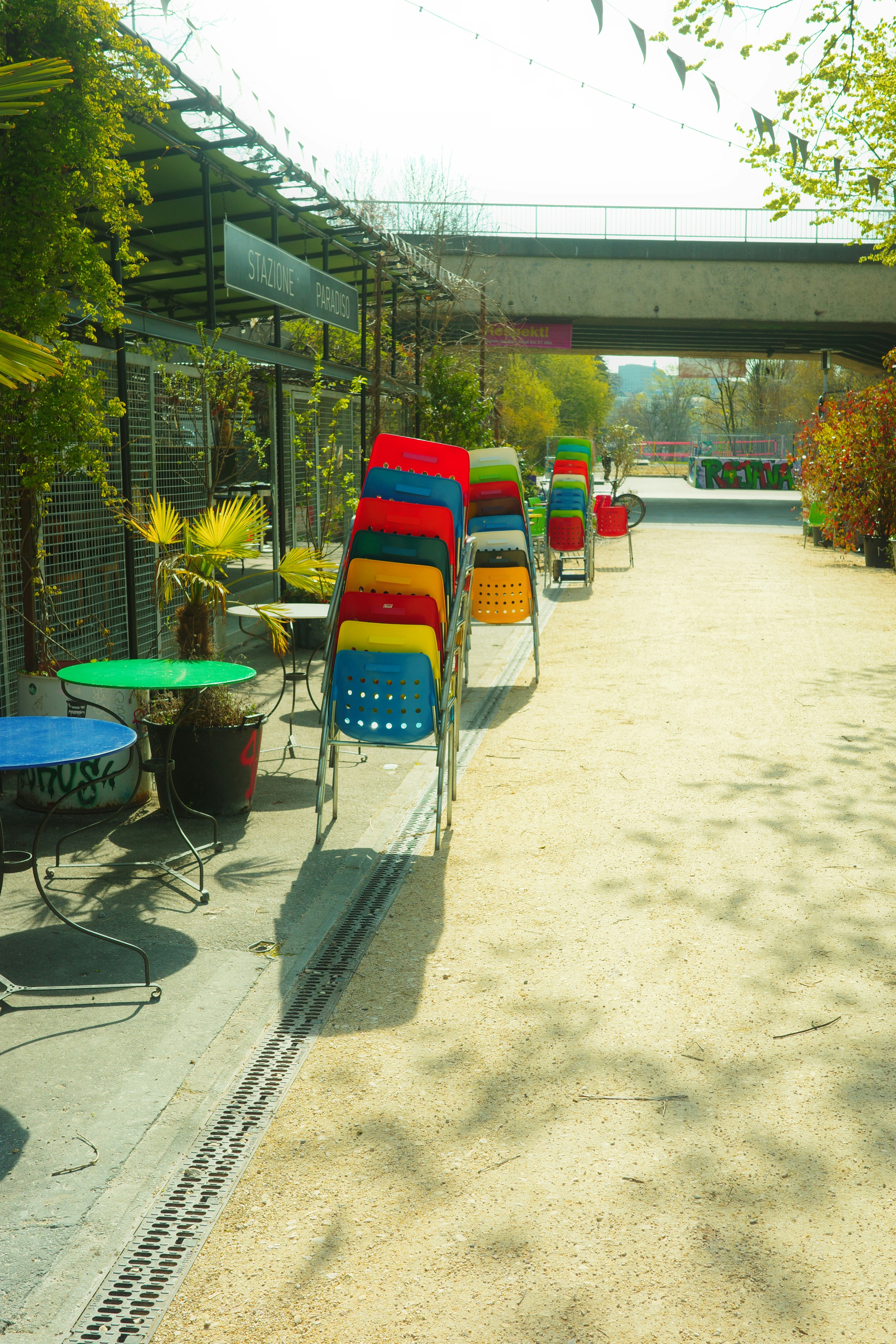 Colorful chairs stacked neatly outside a cafe.
