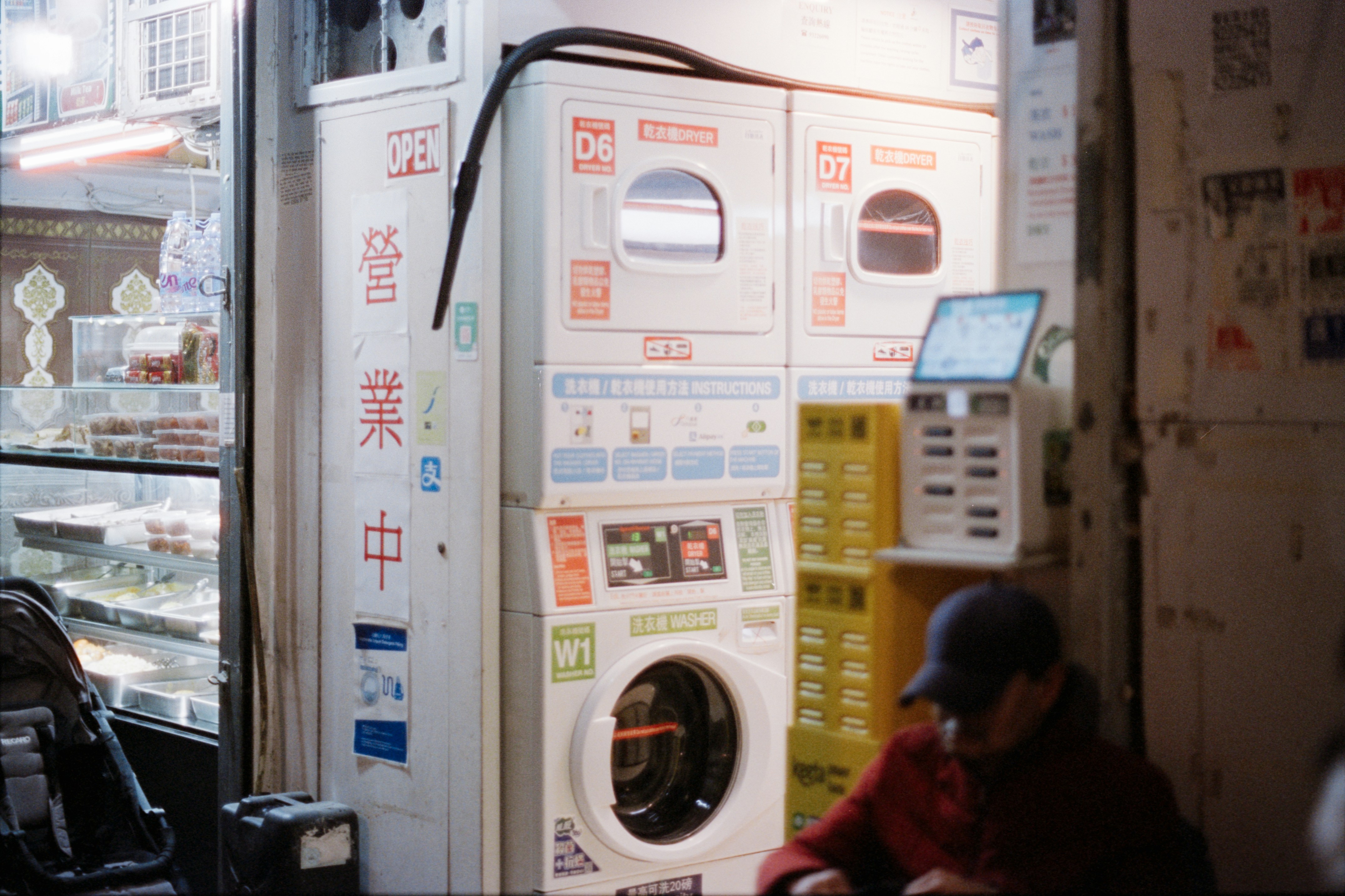 Man sits near stacked washing machines in a laundromat.