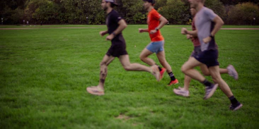 Three men running on a grassy field