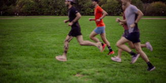 Three men running on a grassy field