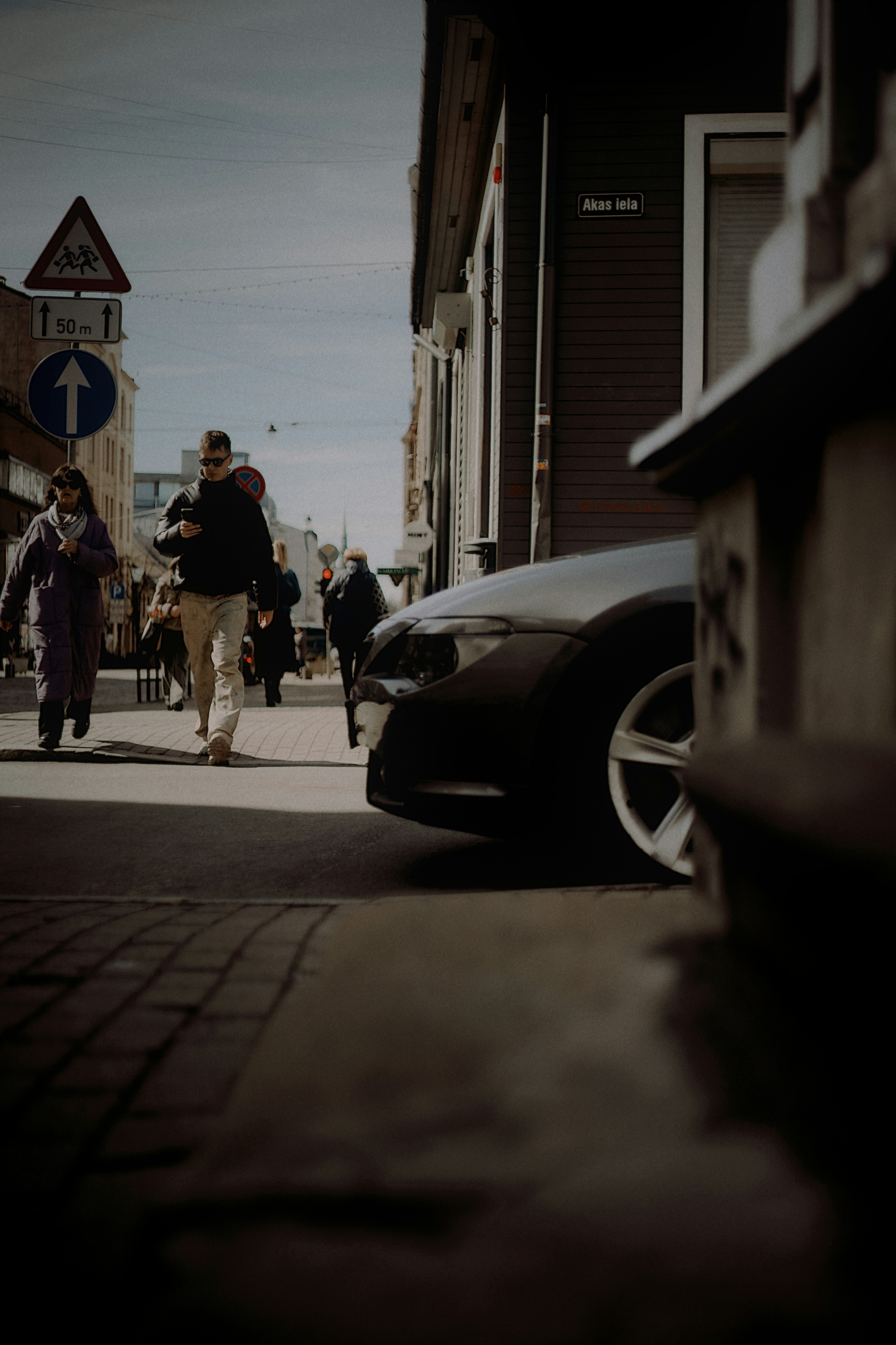 Persone che camminano per strada accanto a un'auto parcheggiata.