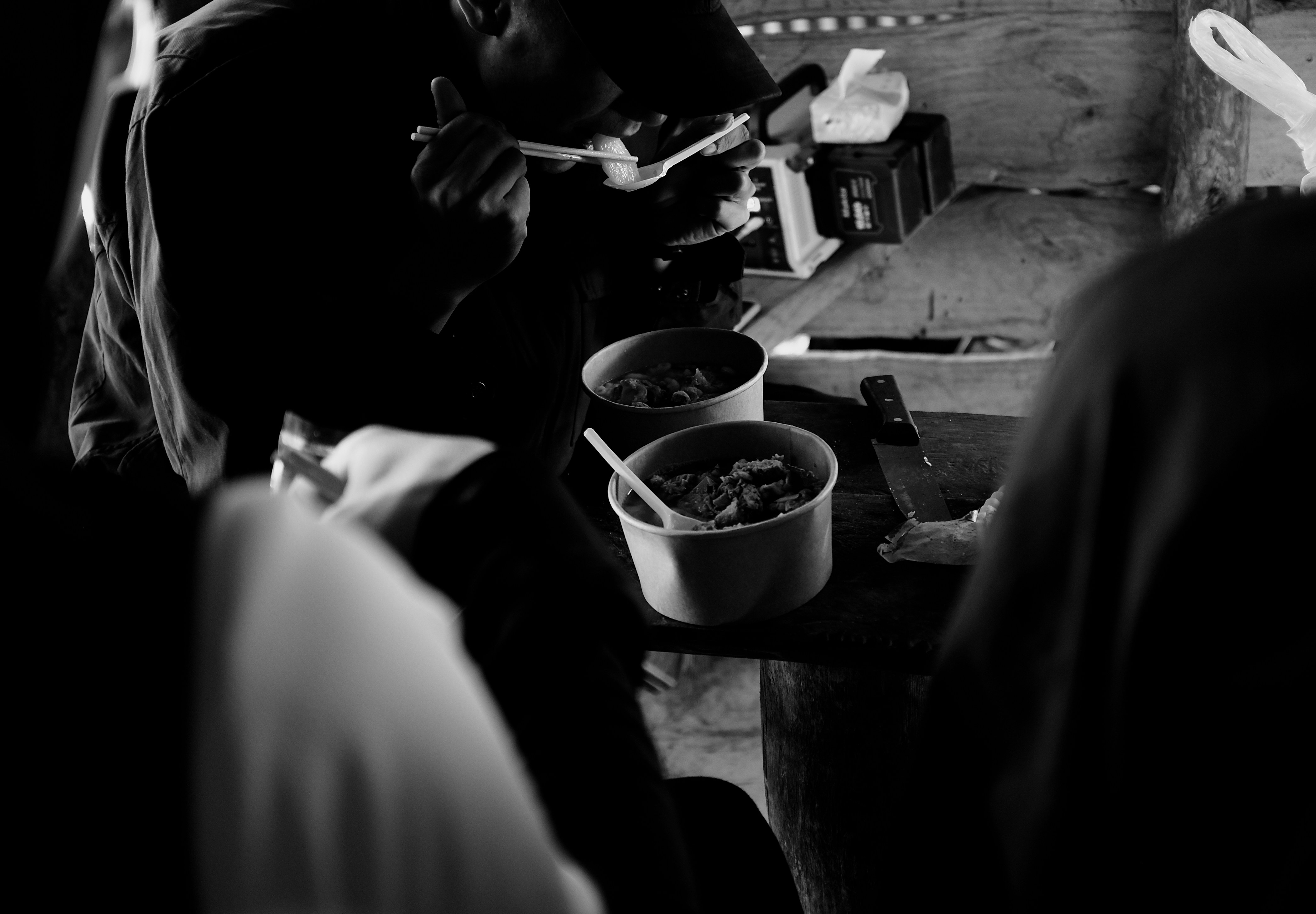 People gathered around food containers at a table.