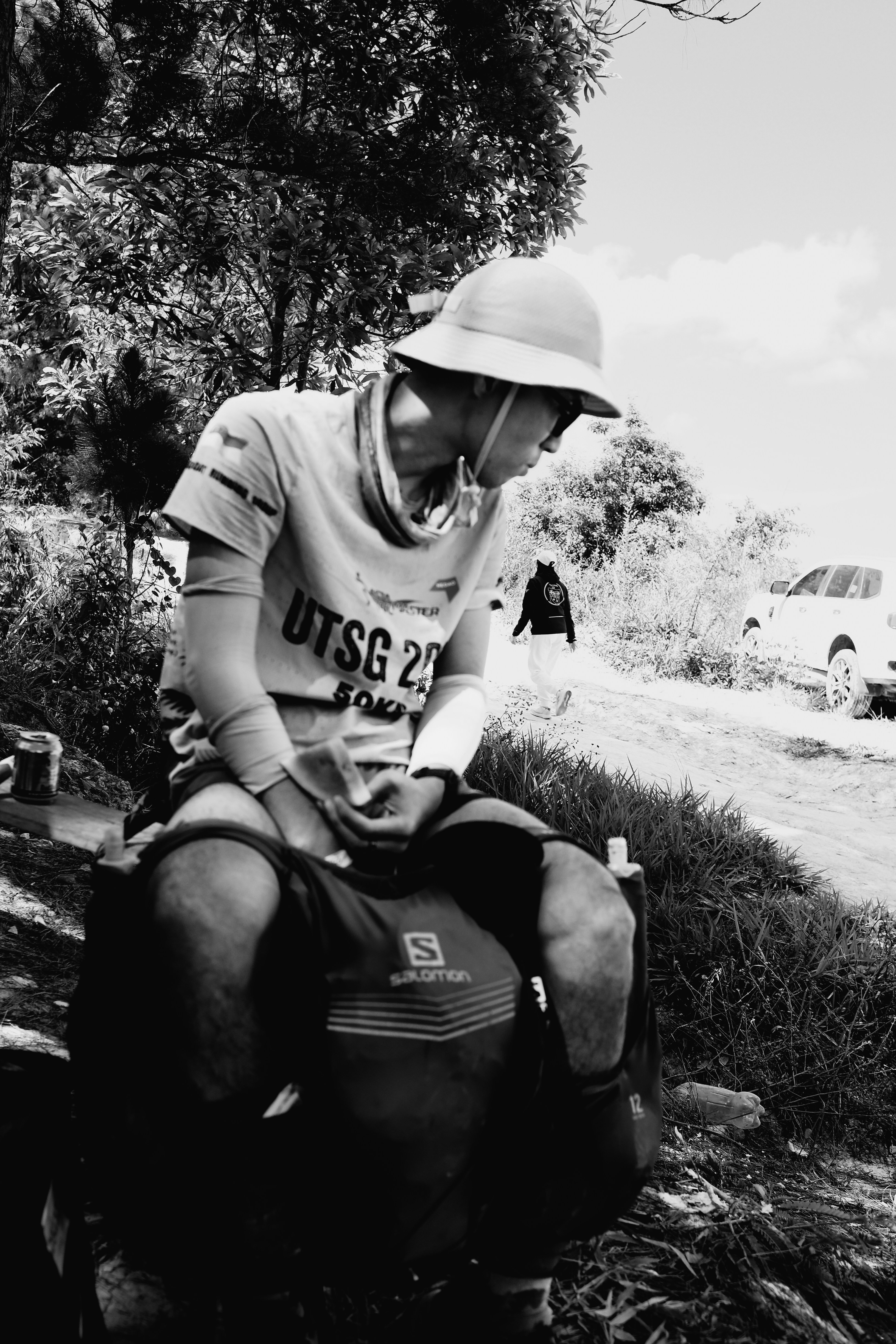Uomo con cappello seduto su uno zaino all'aperto