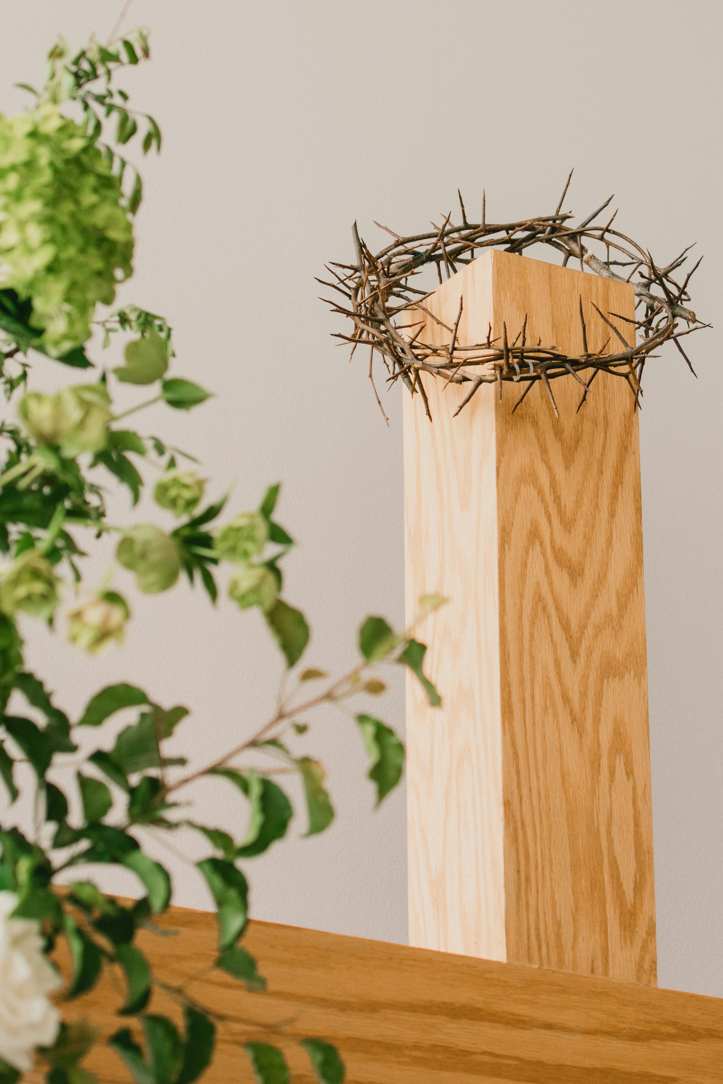 Crown of thorns on a wooden cross with flowers
