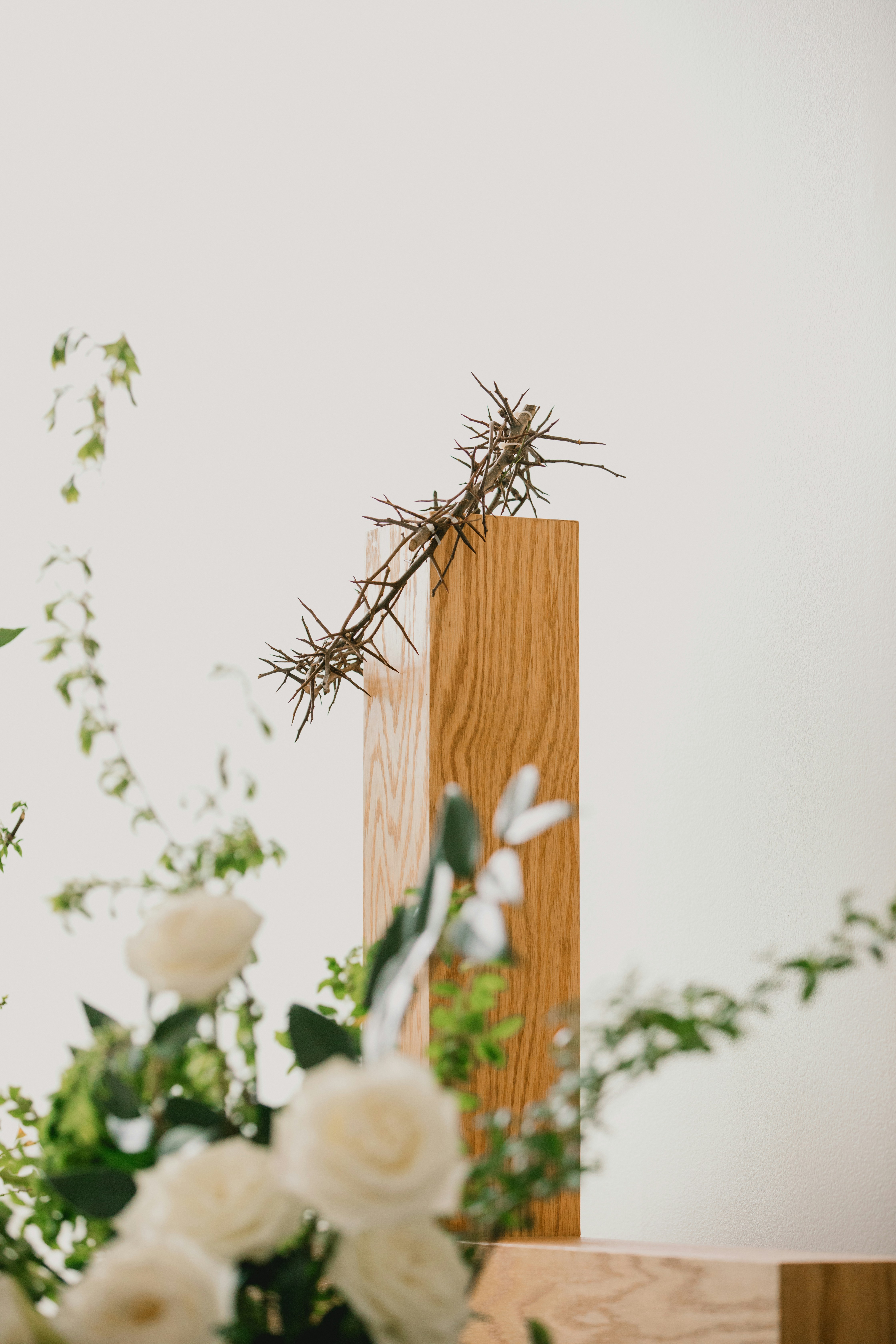 Thorn crown on wooden cross with white roses