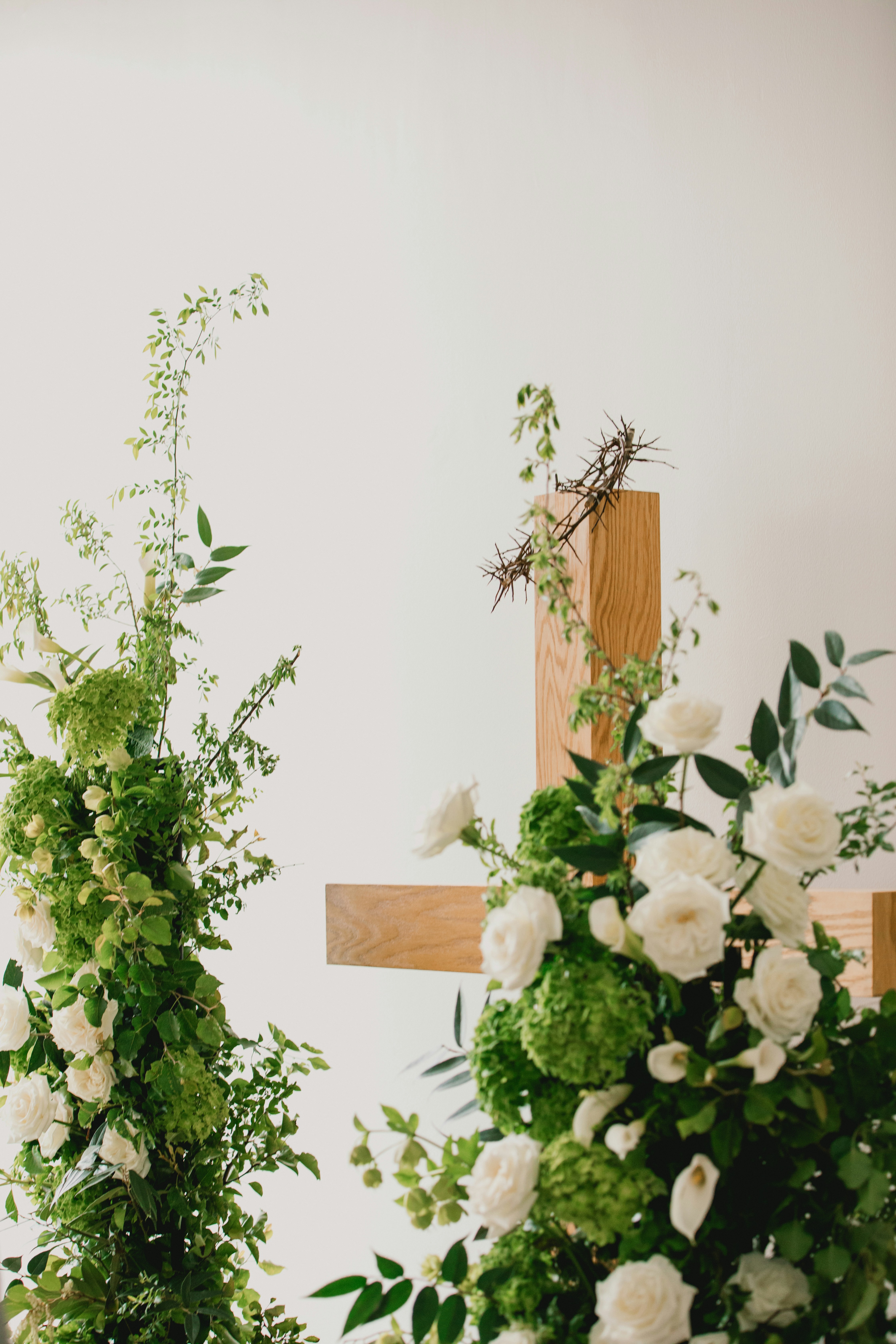 Wooden cross with floral arrangements and crown of thorns