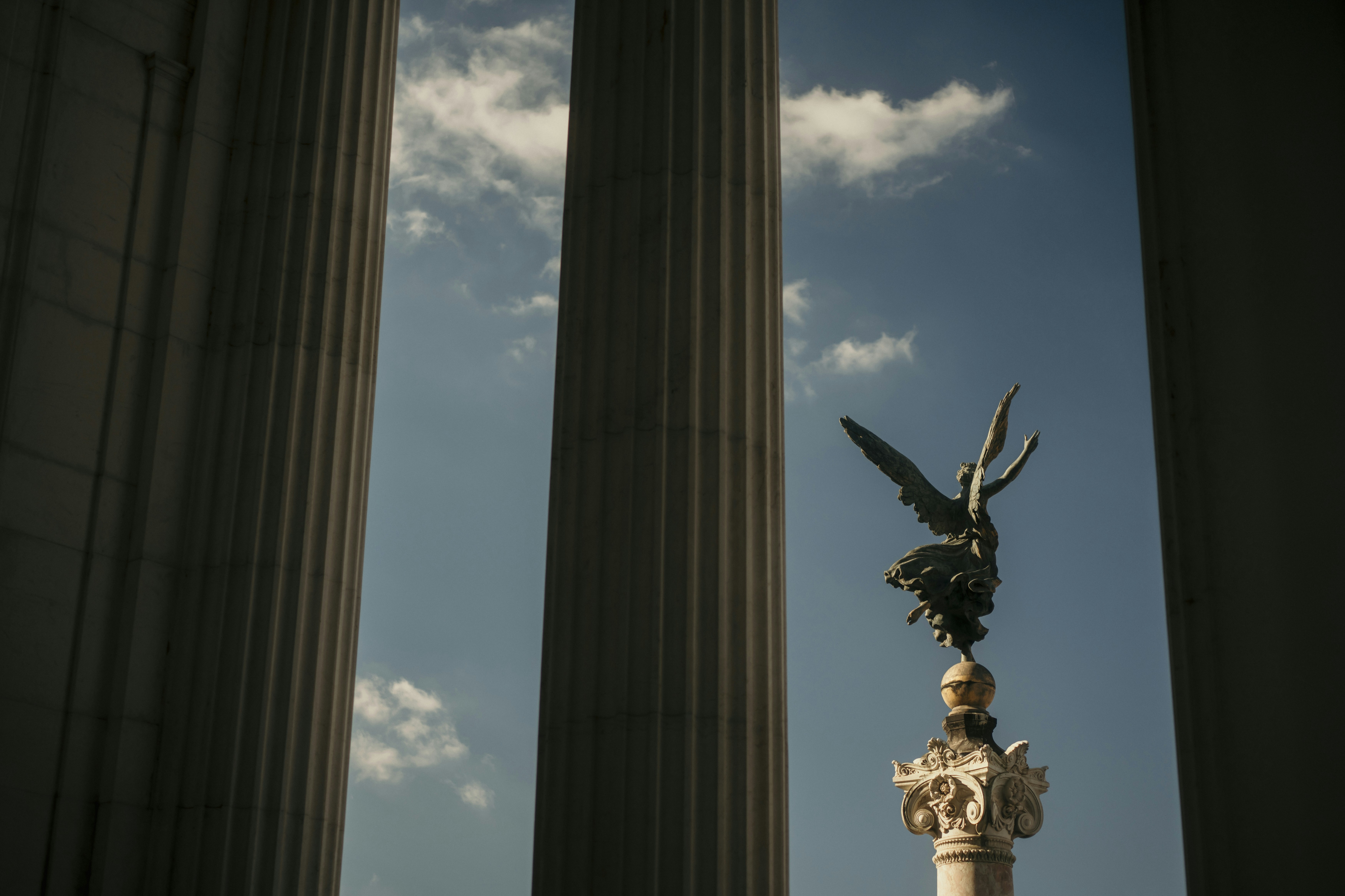 Angelic statue atop a column with classical architecture.