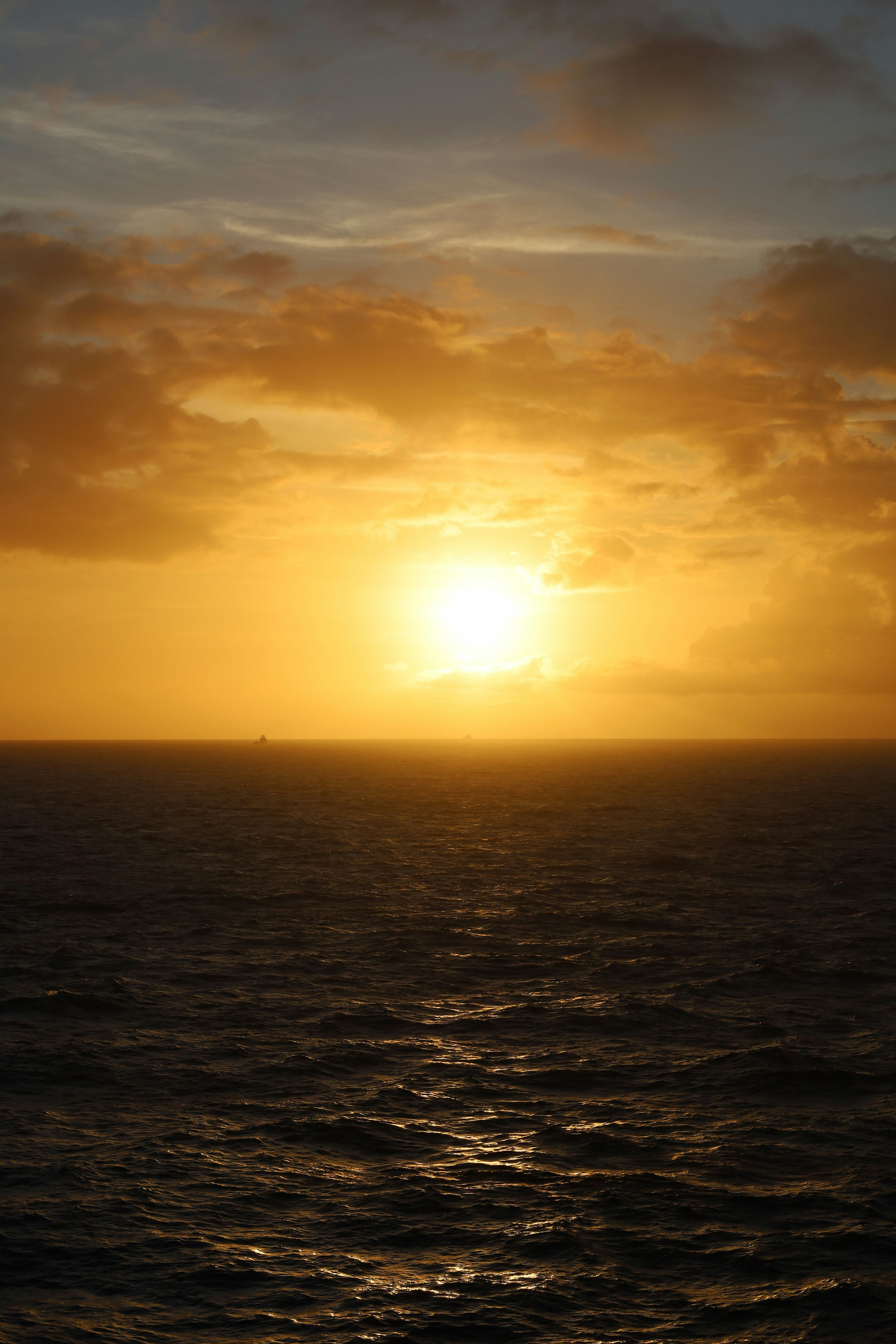 Coucher de soleil doré au-dessus d’un vaste océan sombre.