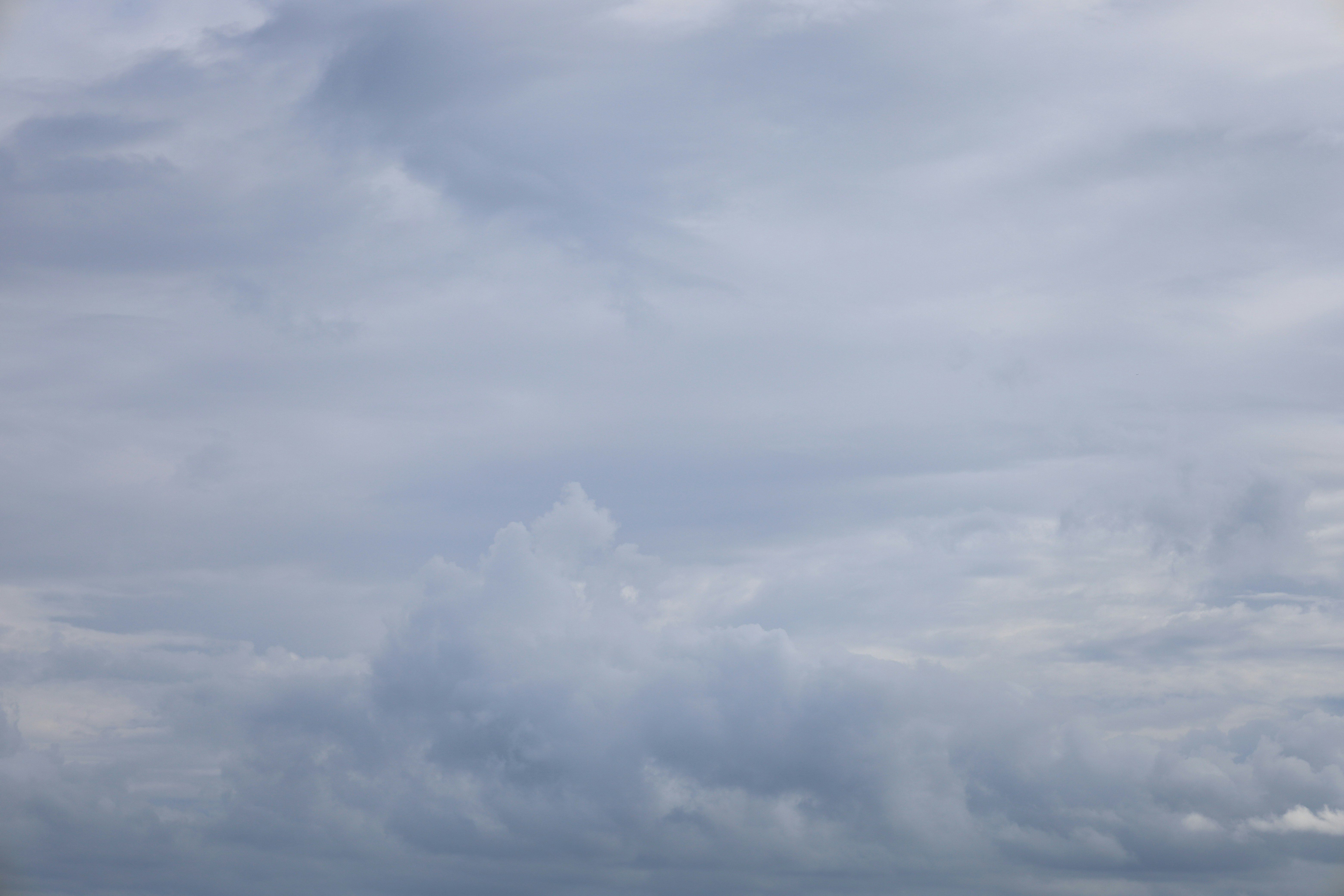 Un ciel nuageux avec de doux nuages gris et blancs.
