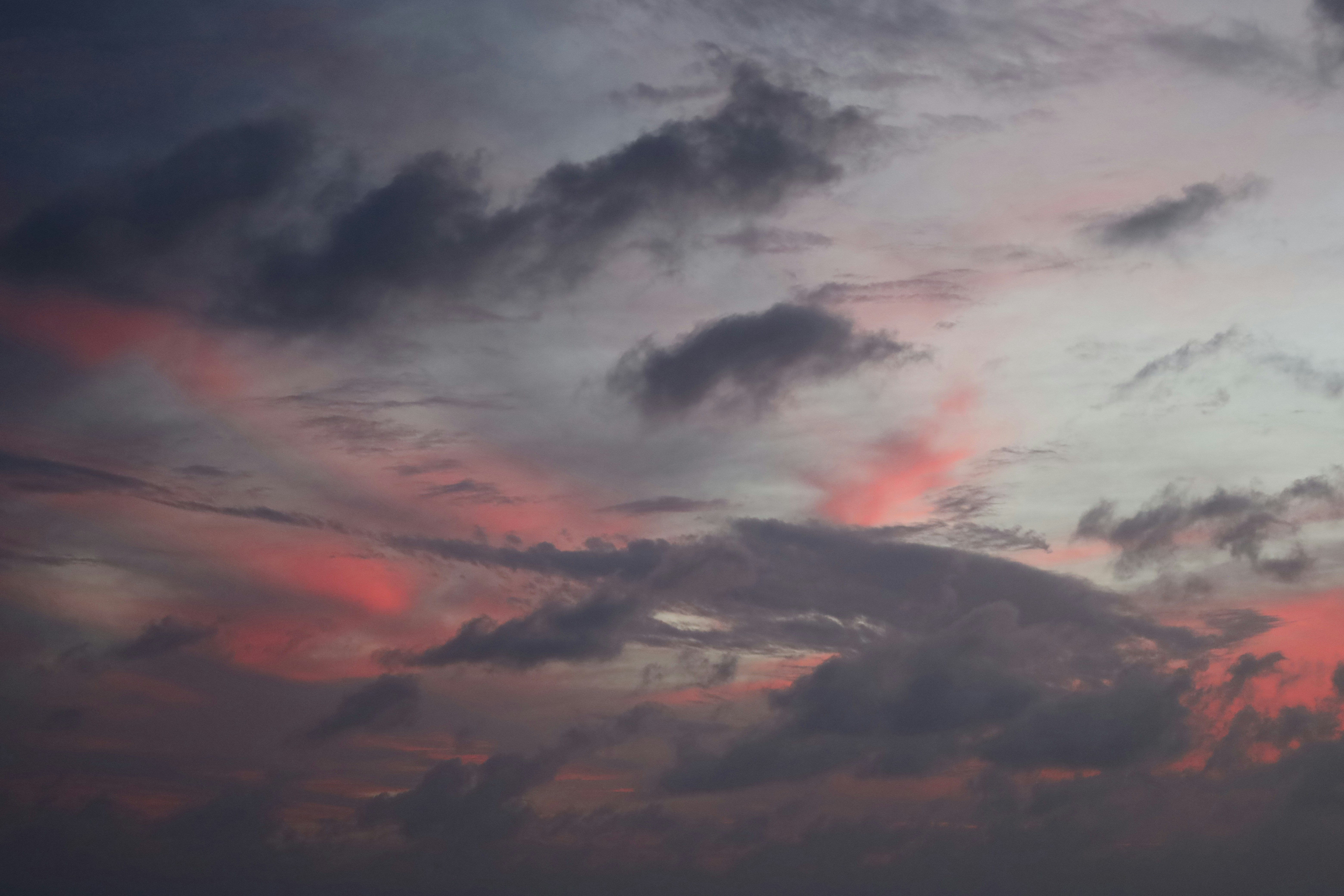 Des nuages dramatiques aux teintes roses et grises au coucher du soleil.