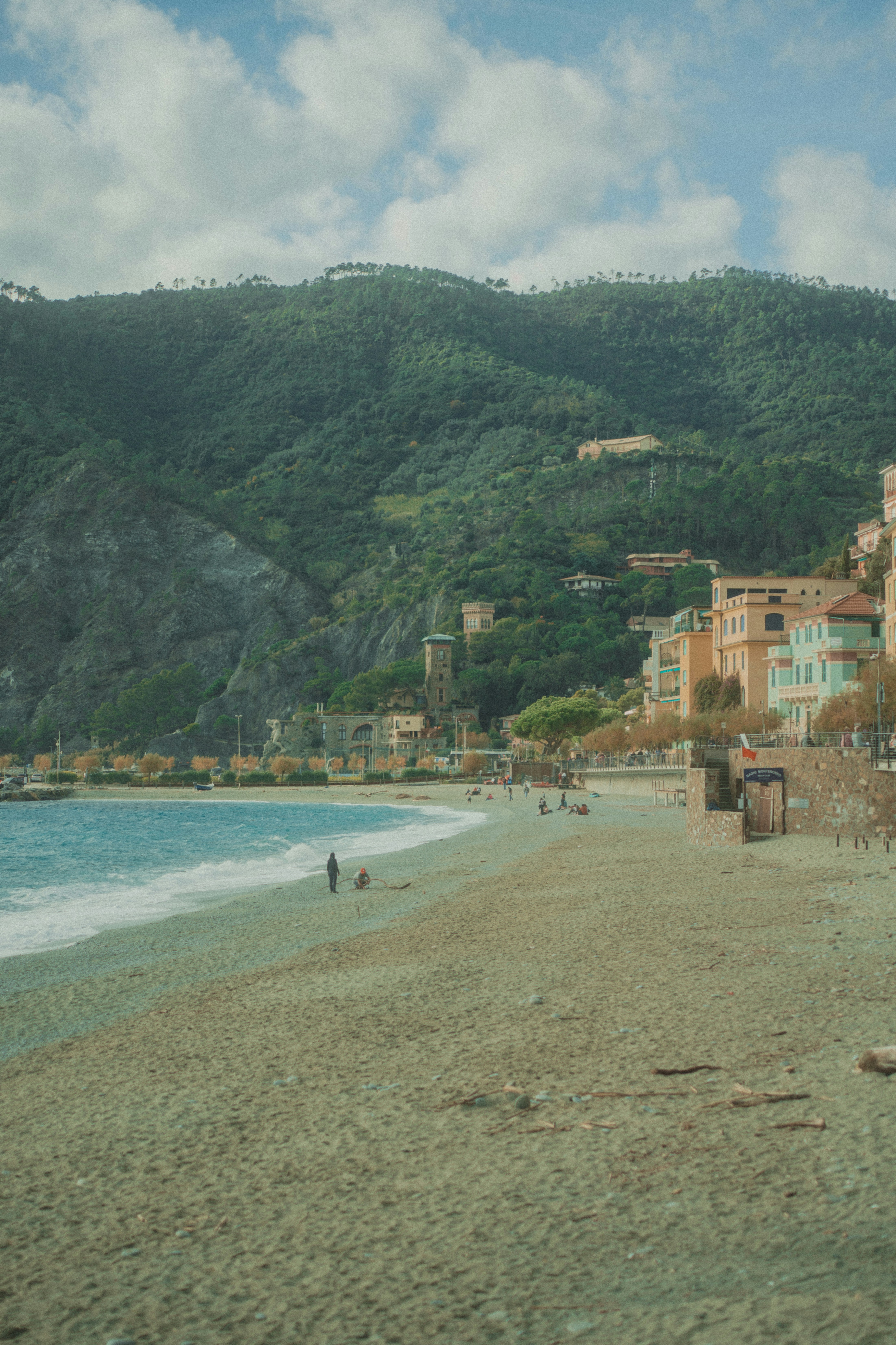 A scenic beach with colorful buildings and green hills.