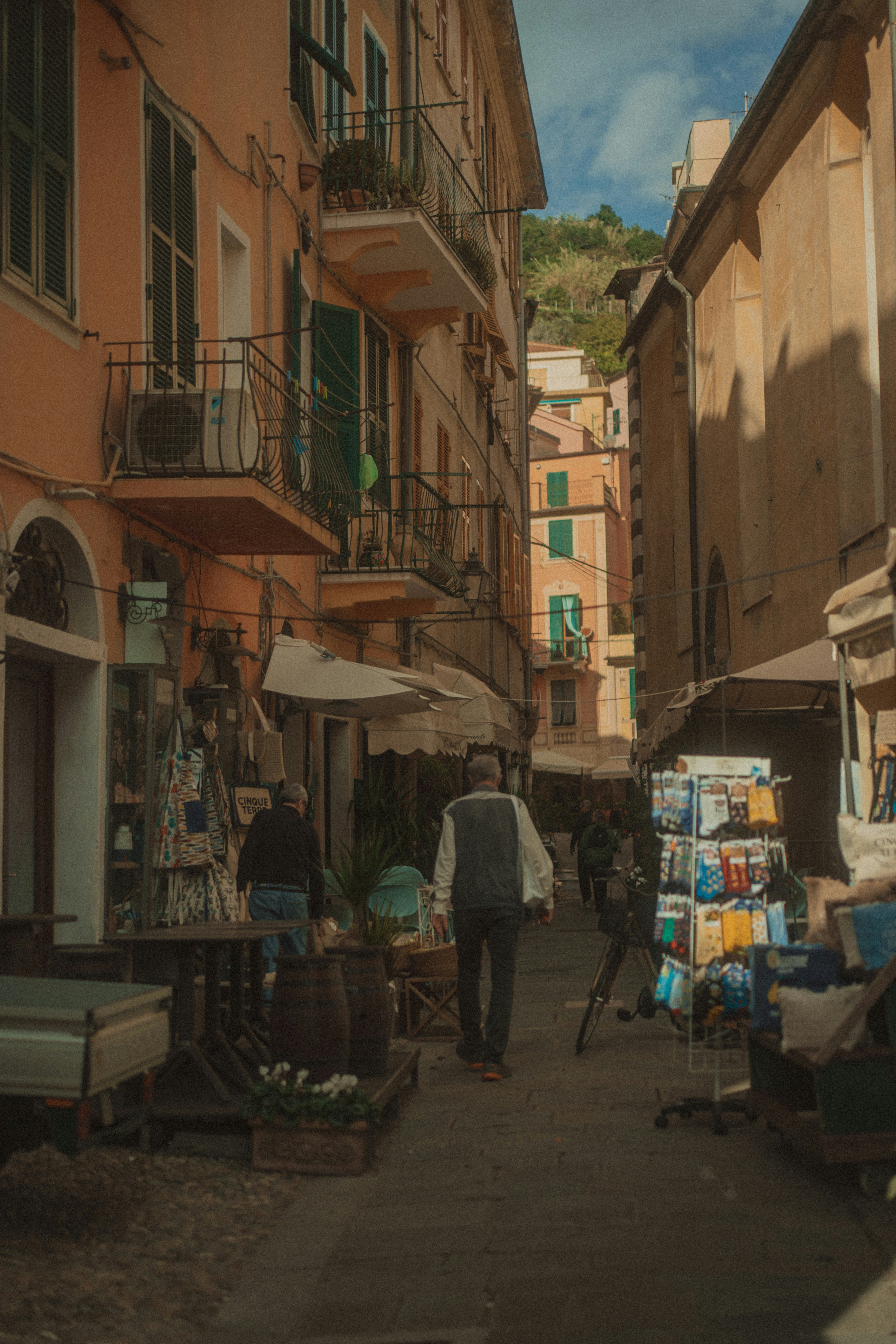 People walk down a narrow street lined with buildings.