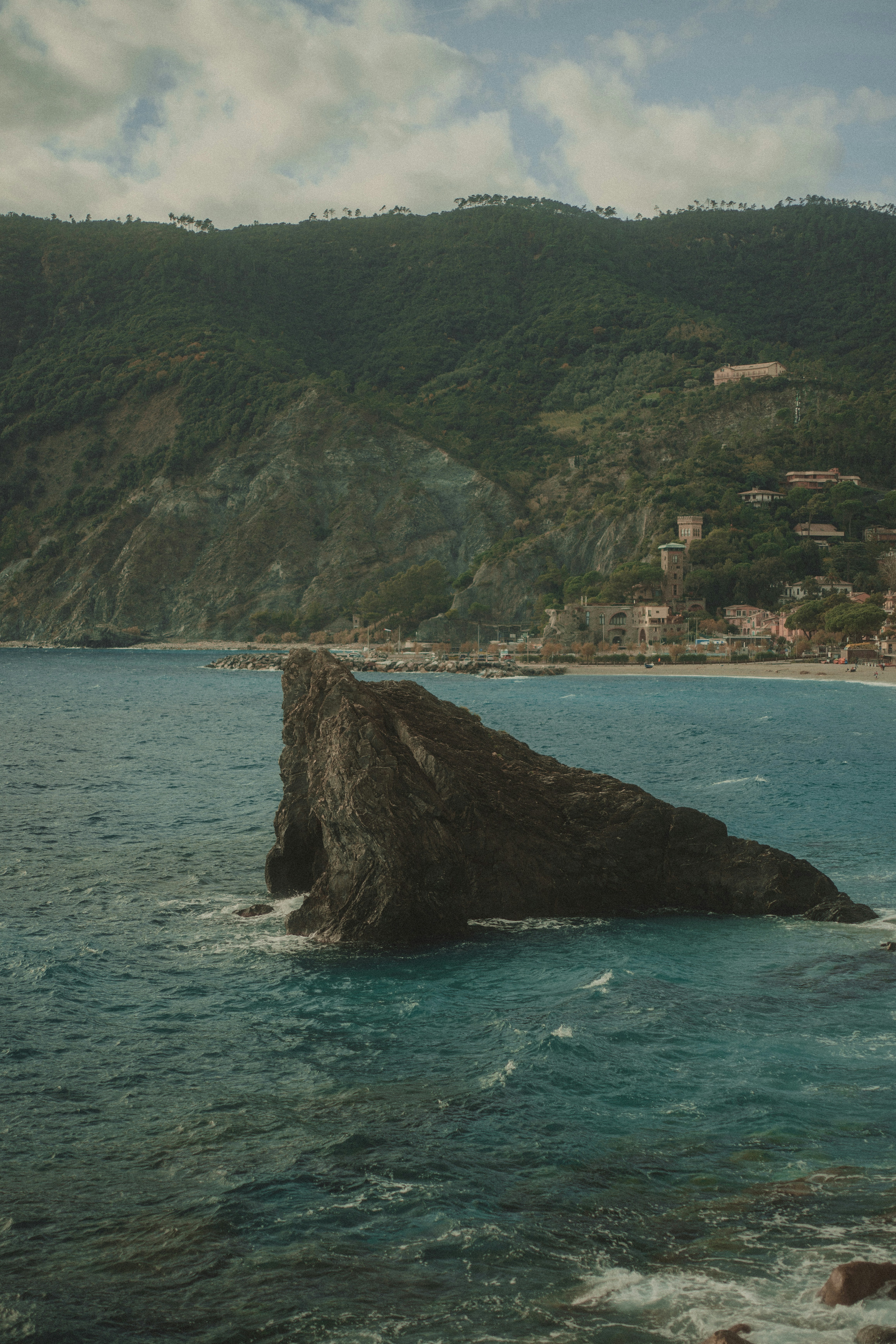 A large rock formation in the ocean near a coastline.