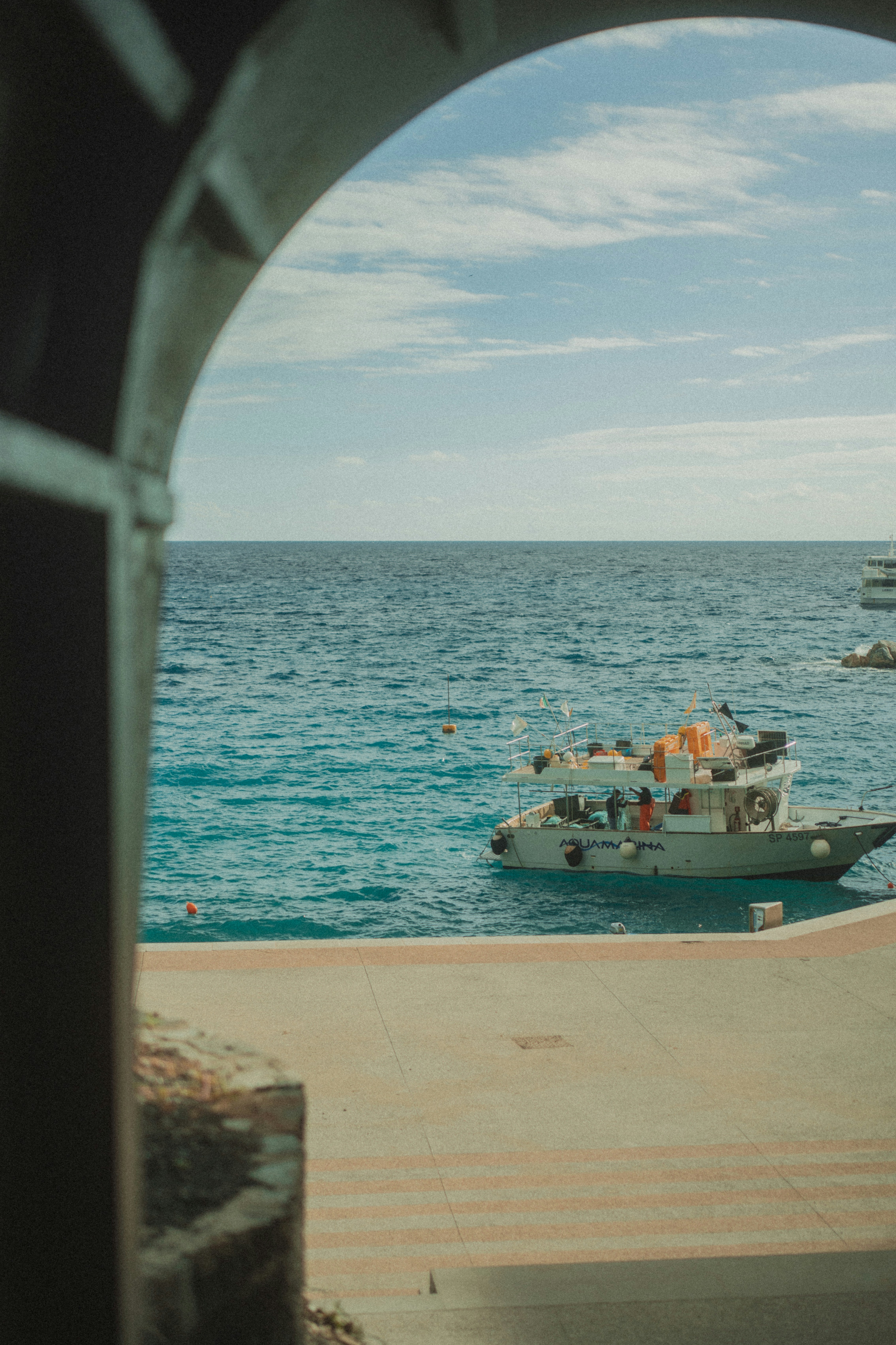 Boat floating on blue ocean water near shore.