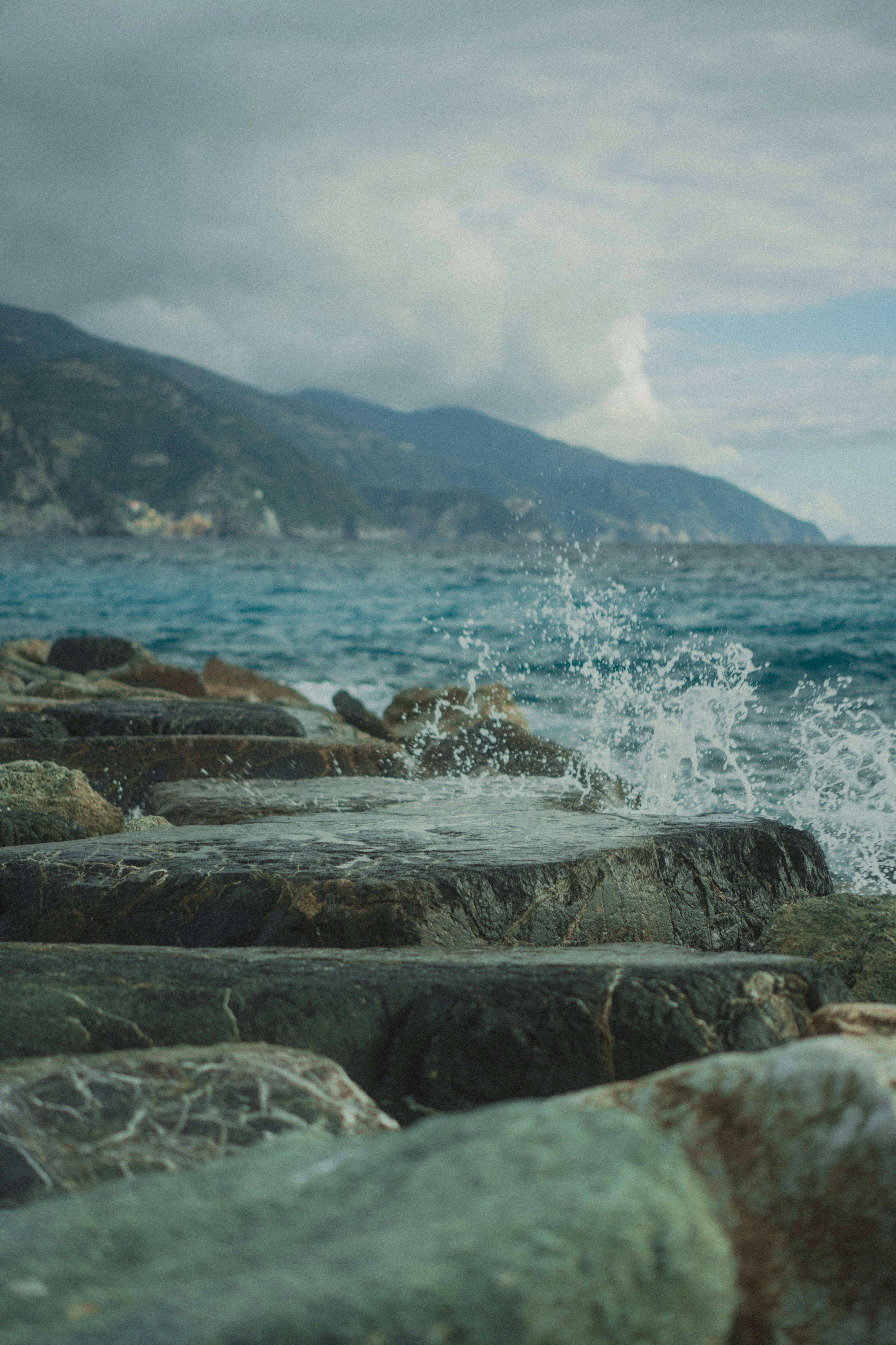 Waves crashing on rocky shore with mountains in background