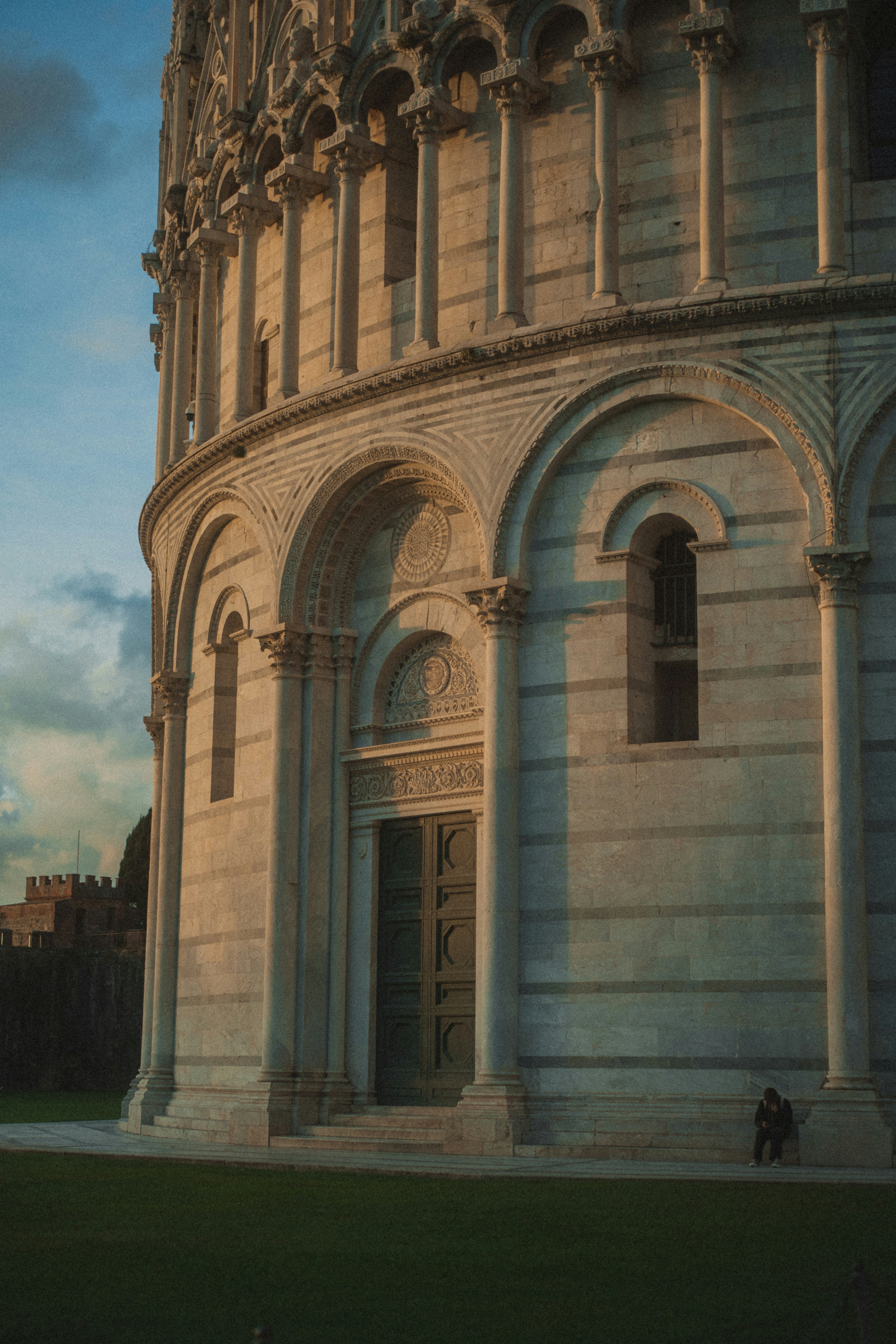 A person sits near the base of a marble building.