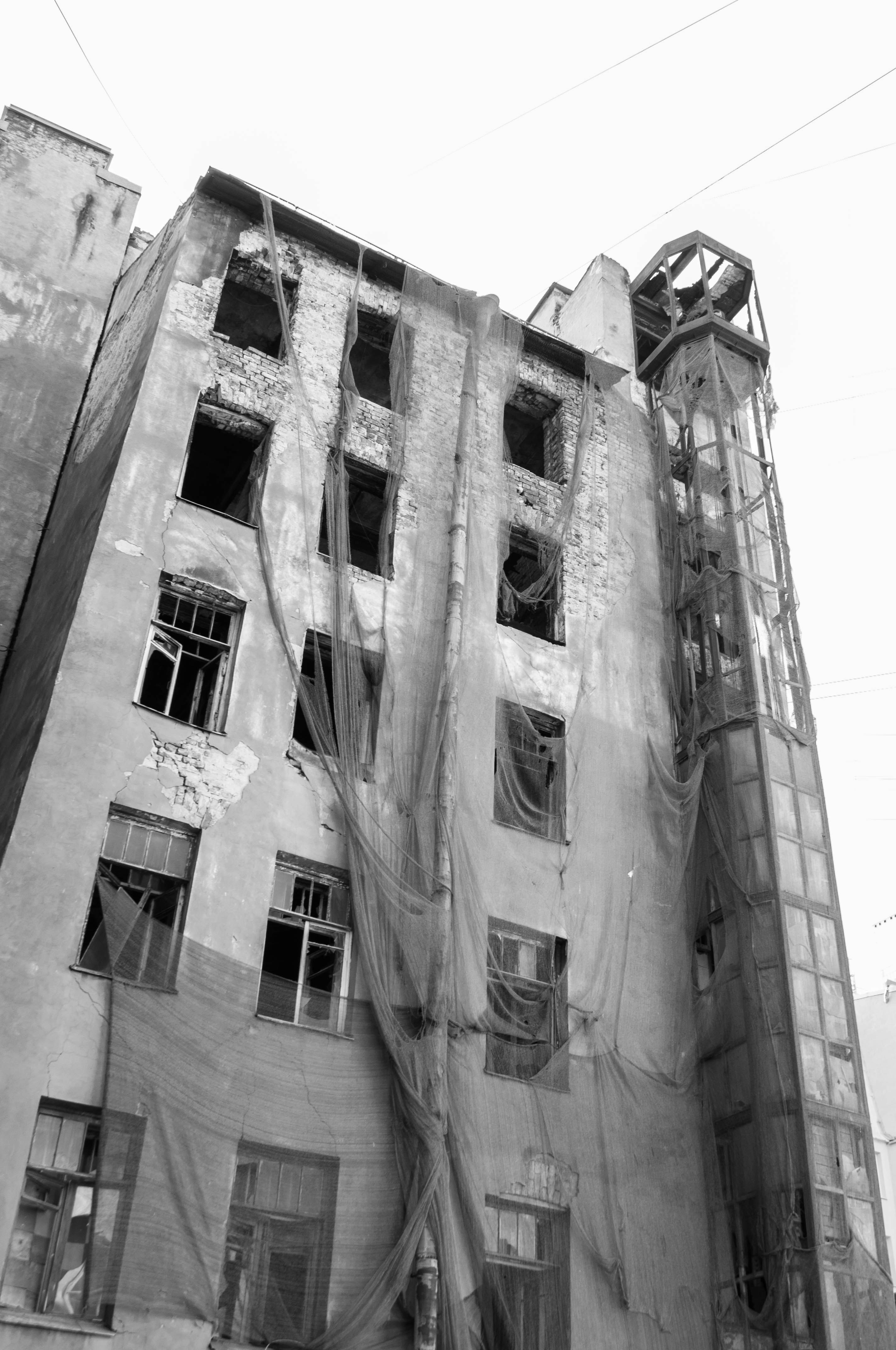 Dilapidated building with torn netting and broken windows