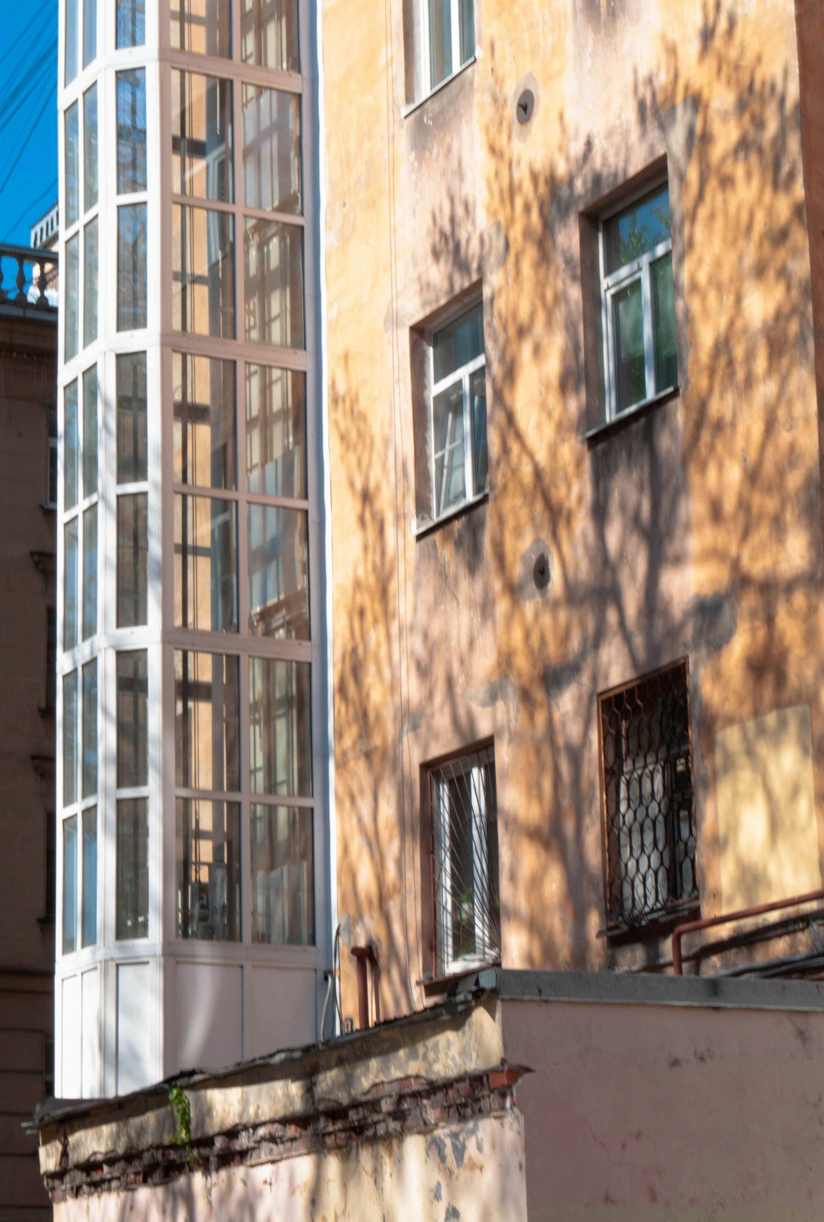 Tall building with glass elevator shaft and windows.