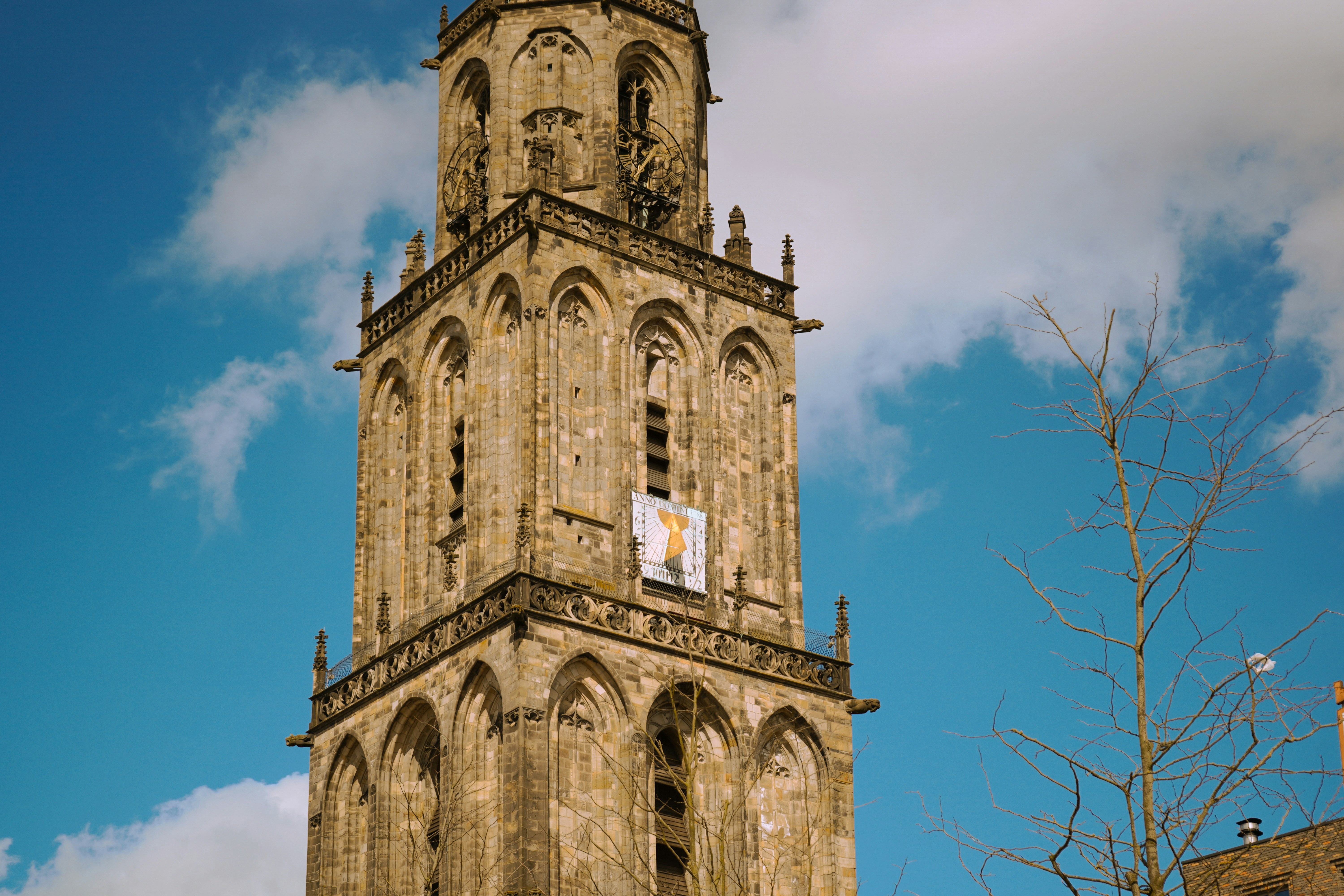 Aannemer Groningen — Tall stone tower with arched windows against blue sky — Aannemer in Groningen: kosten, vergunning en lokale tips voo