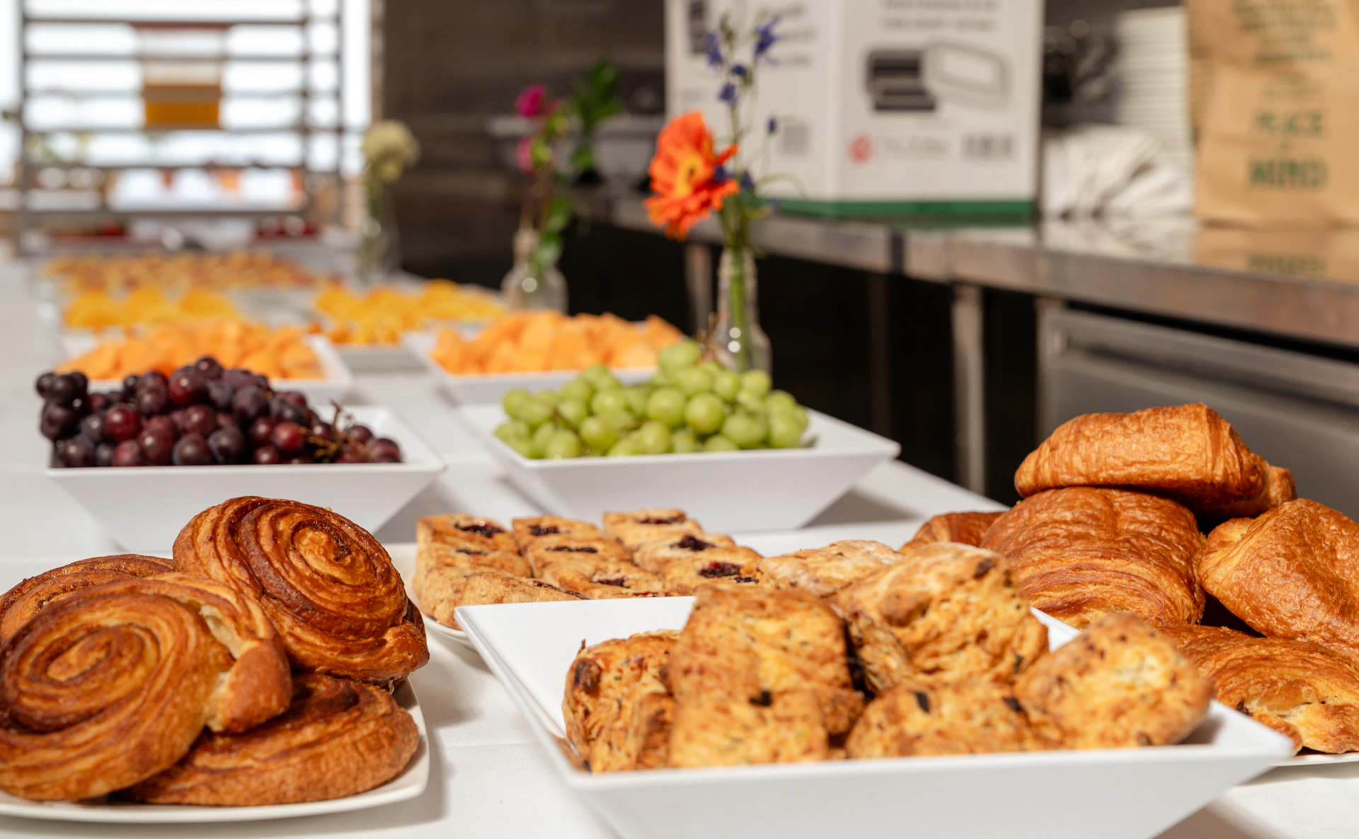 Assortment of pastries, fruits, and grapes on a buffet table.