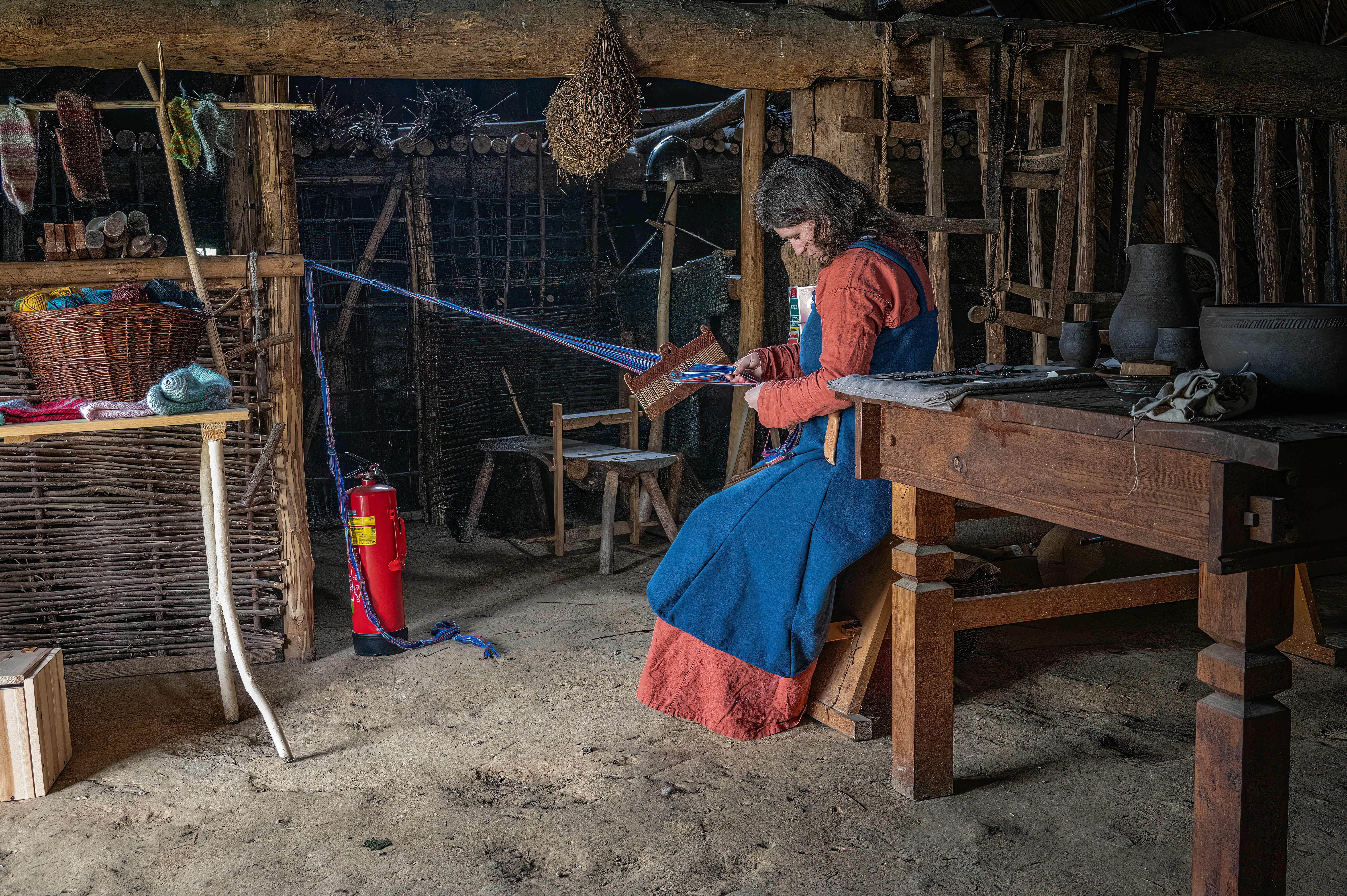 Woman weaving on a loom in a rustic workshop.