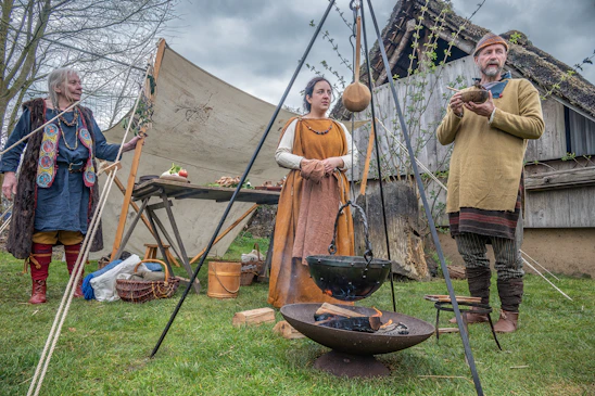 People in historical clothing gathered around a campfire.