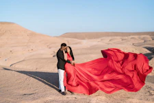 Couple in red dress embracing in desert landscape