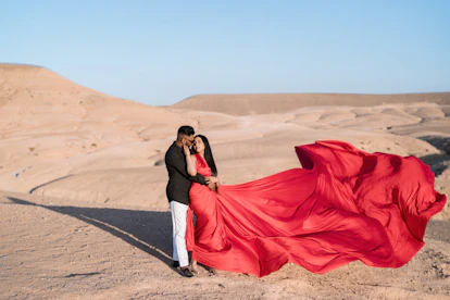 Couple in red dress embracing in desert landscape