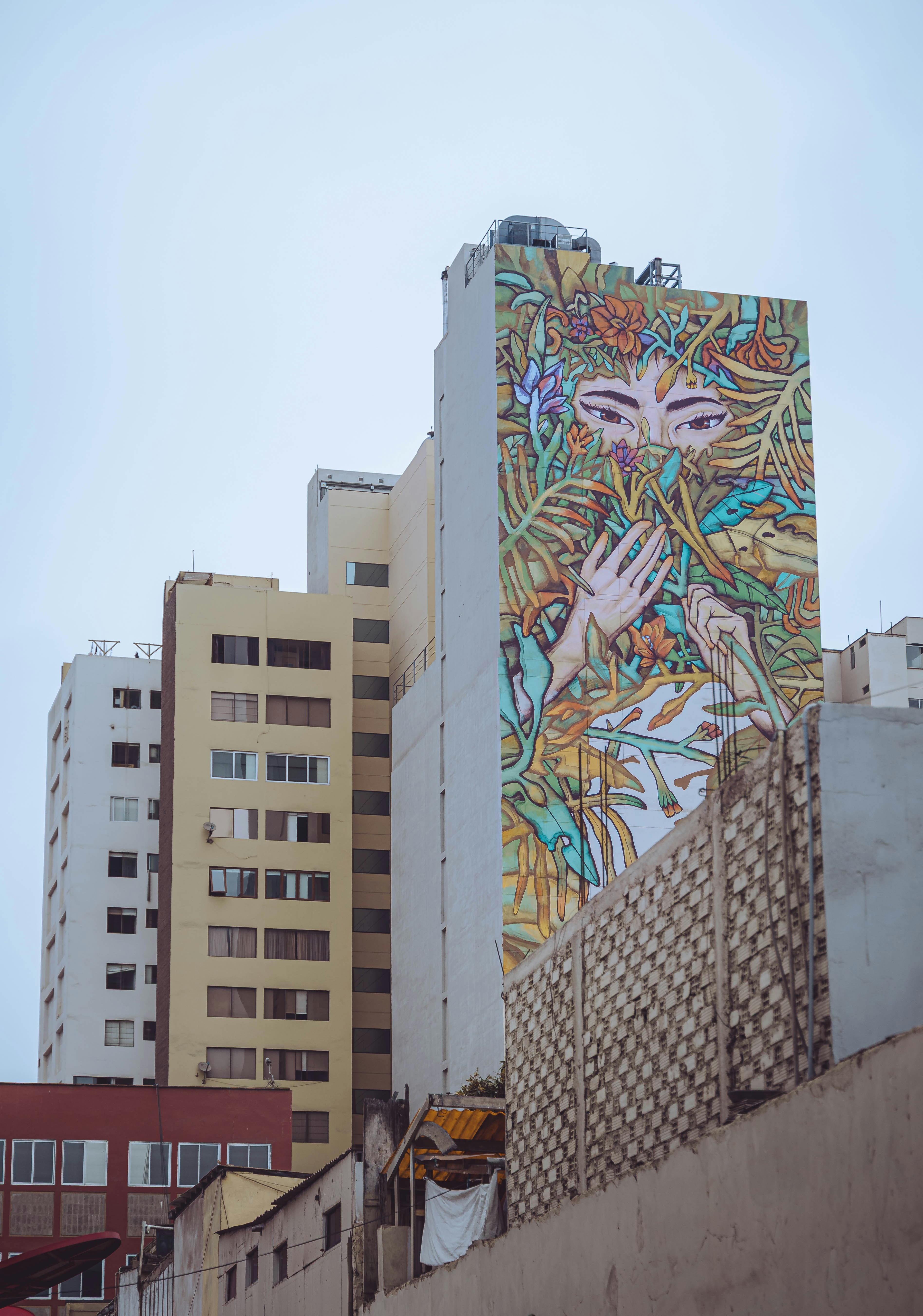 Building with large mural of a woman and plants