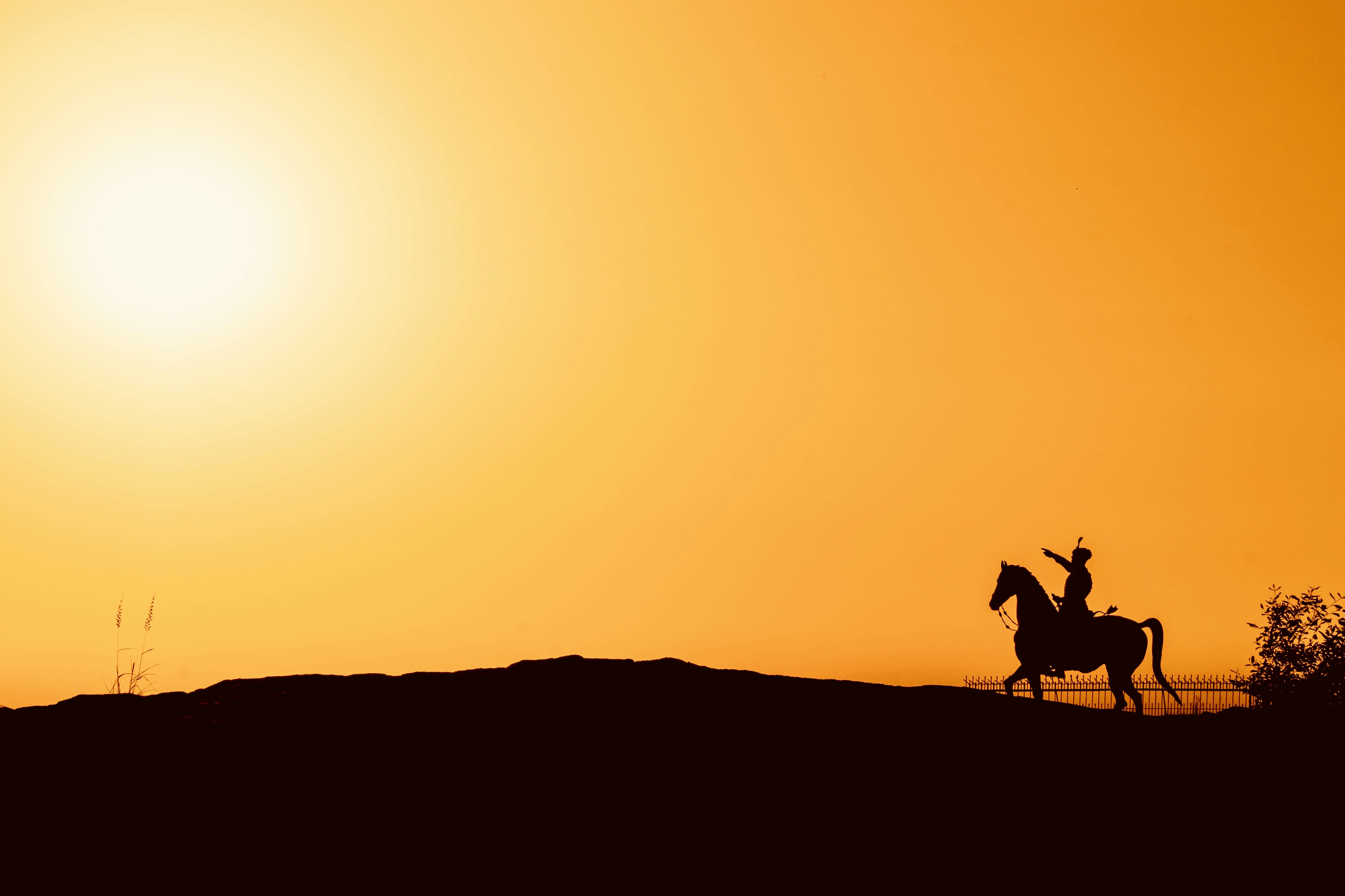 Silhouette of a person riding a horse at sunset.