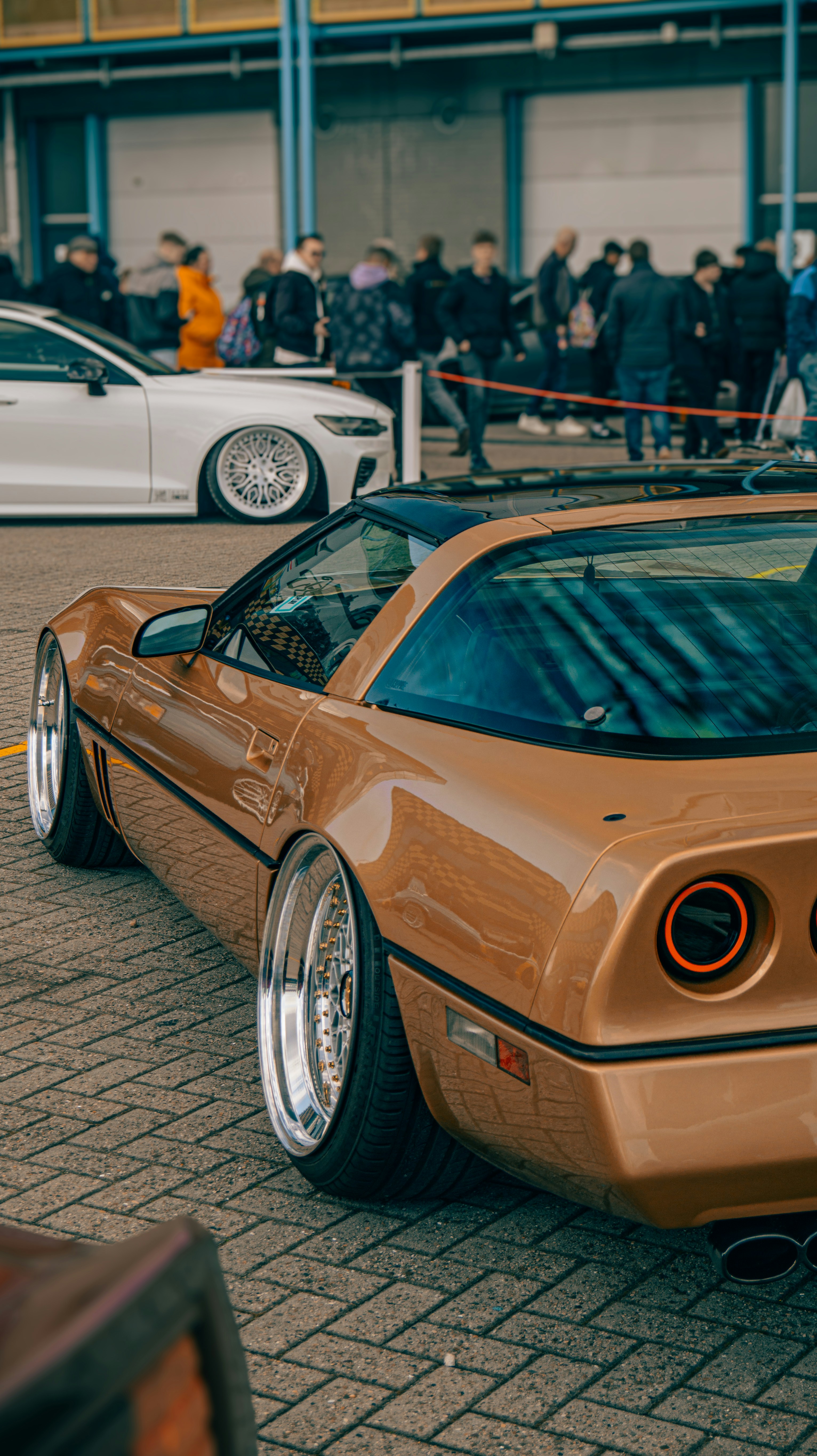A gold sports car with chrome rims parked outside.