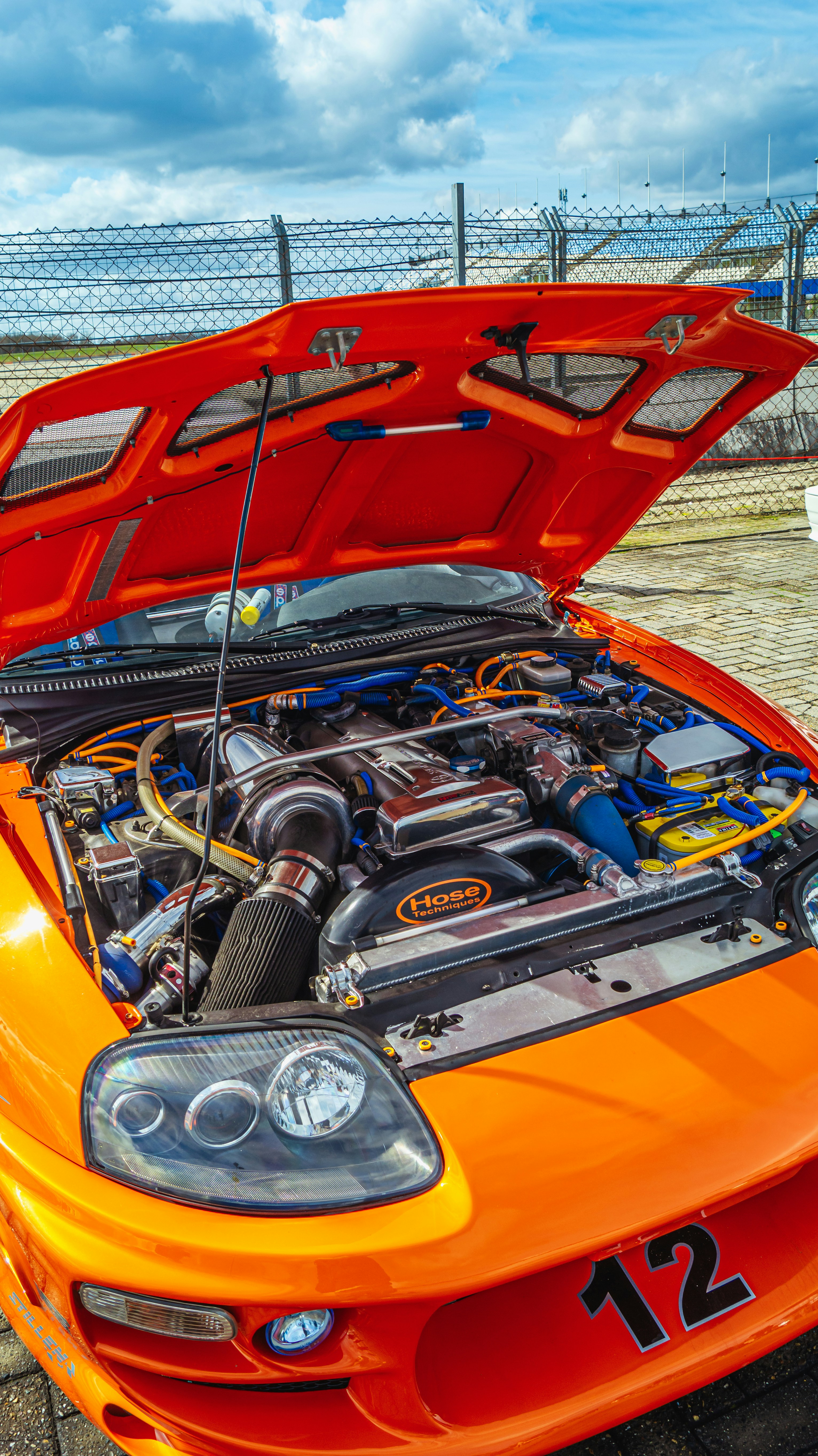 Orange sports car with engine exposed at racetrack