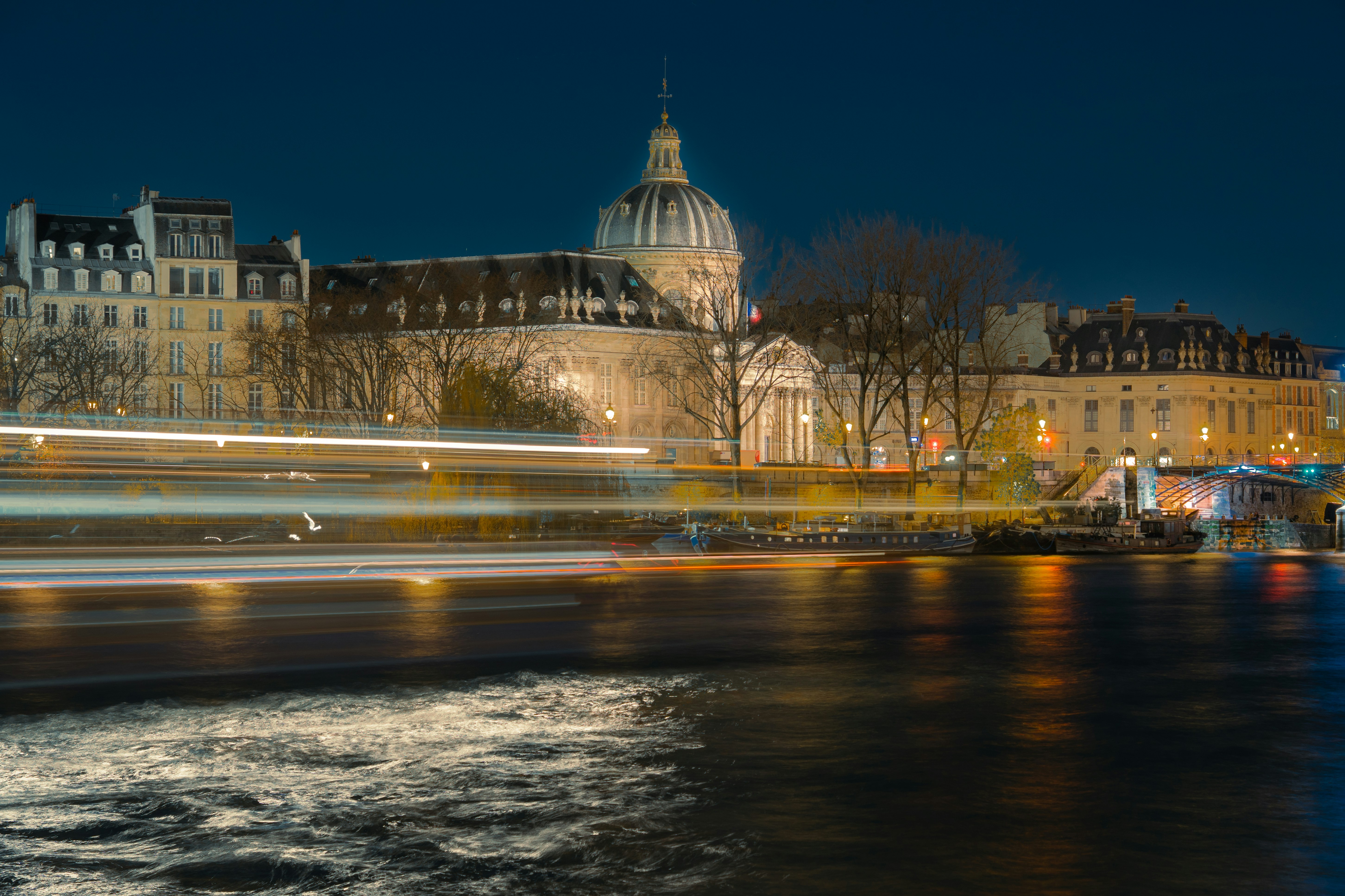 Paysage urbain avec des traînées lumineuses sur l’eau la nuit