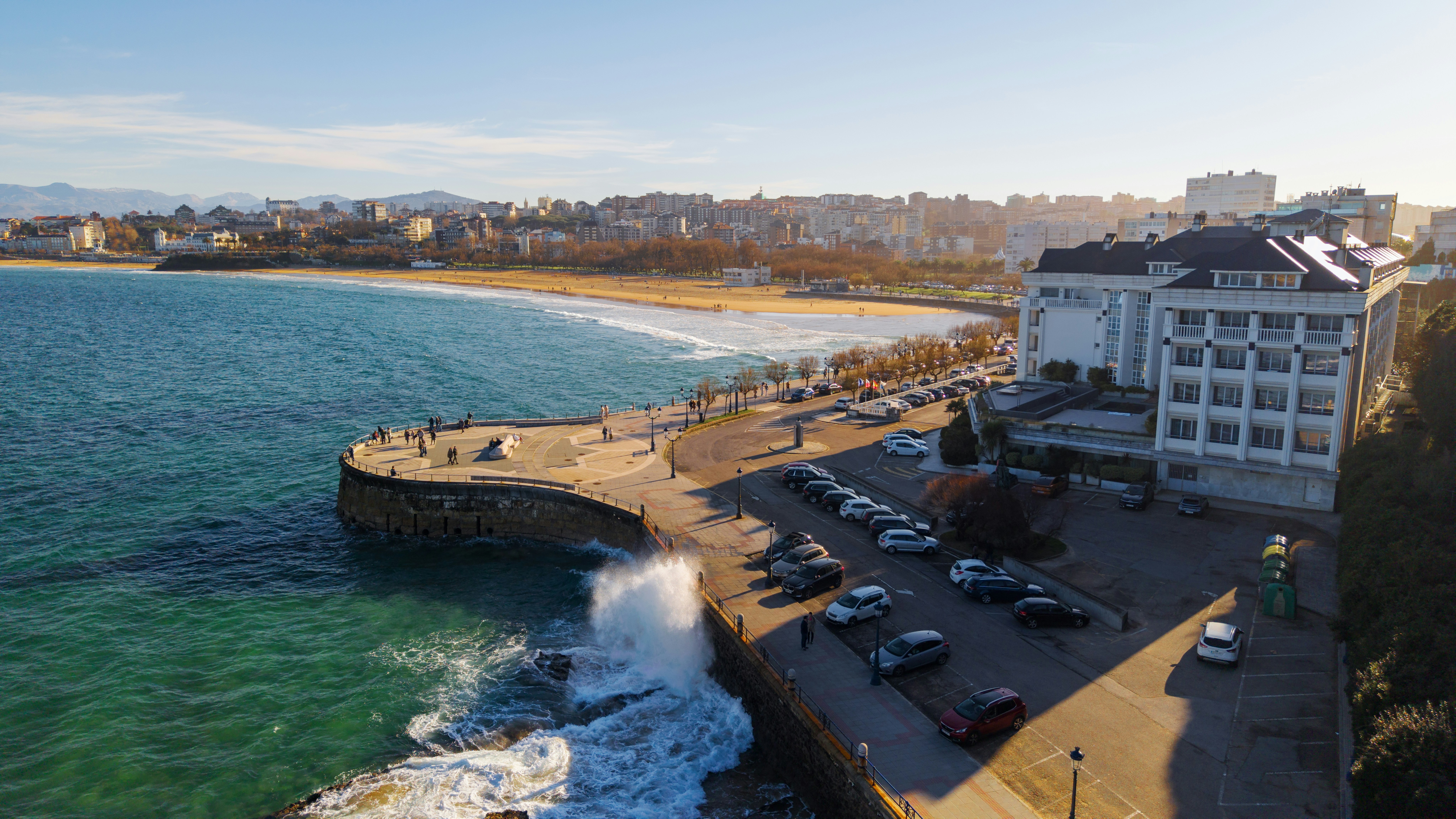 Coastal city with a promenade and ocean waves crashing.