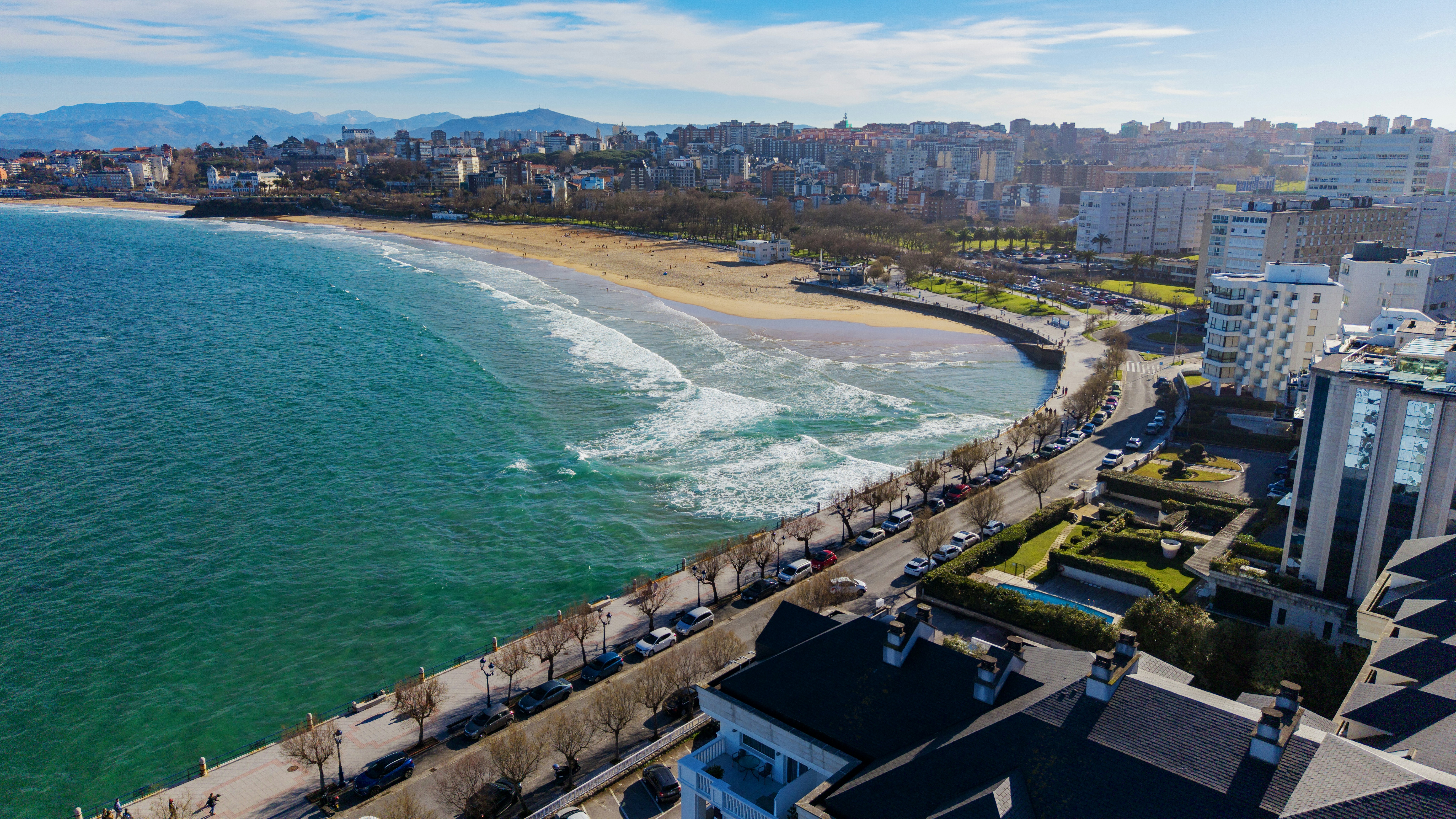 Coastal city skyline with a beach and ocean waves.
