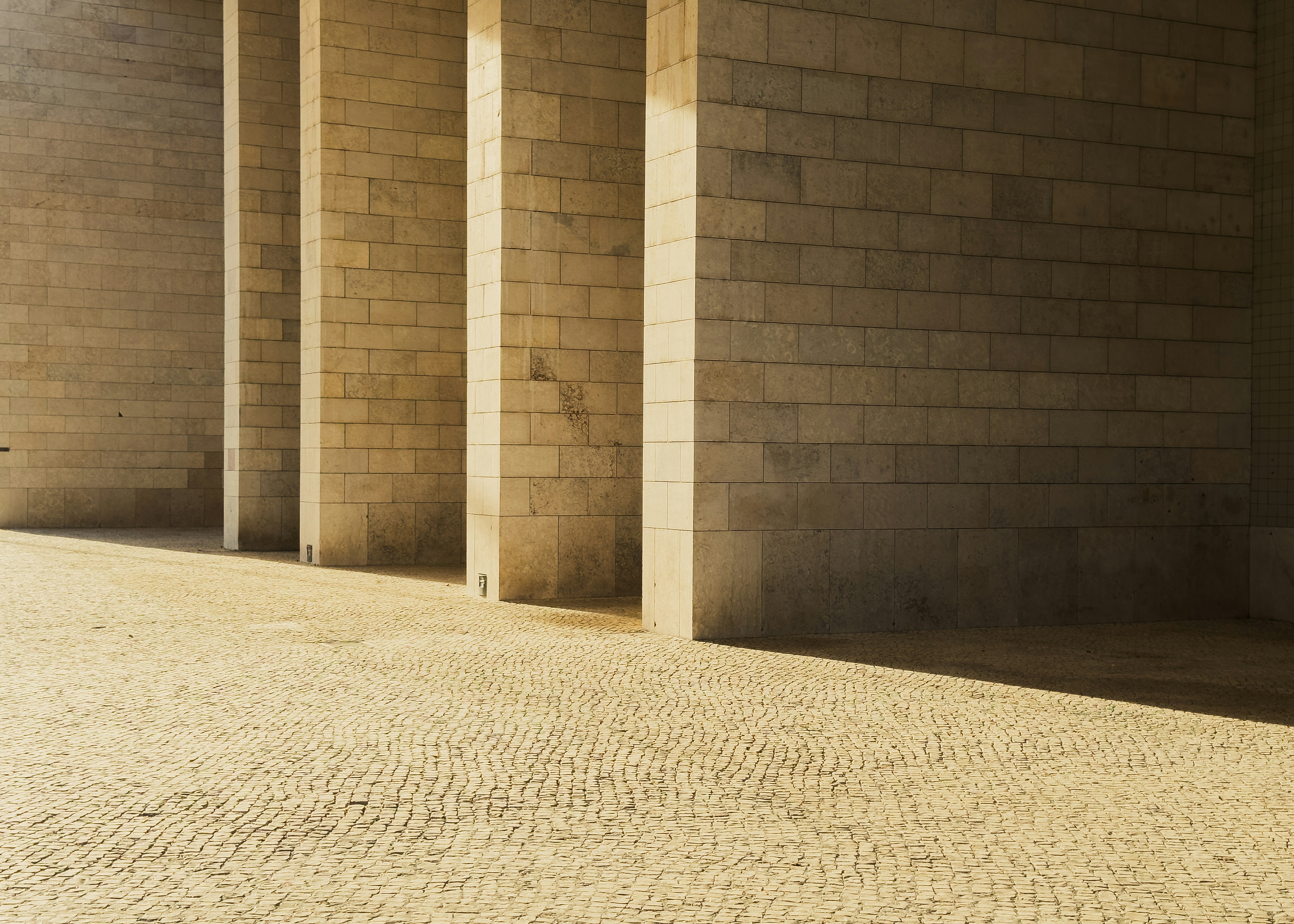 Stone pillars casting long shadows on a cobblestone path