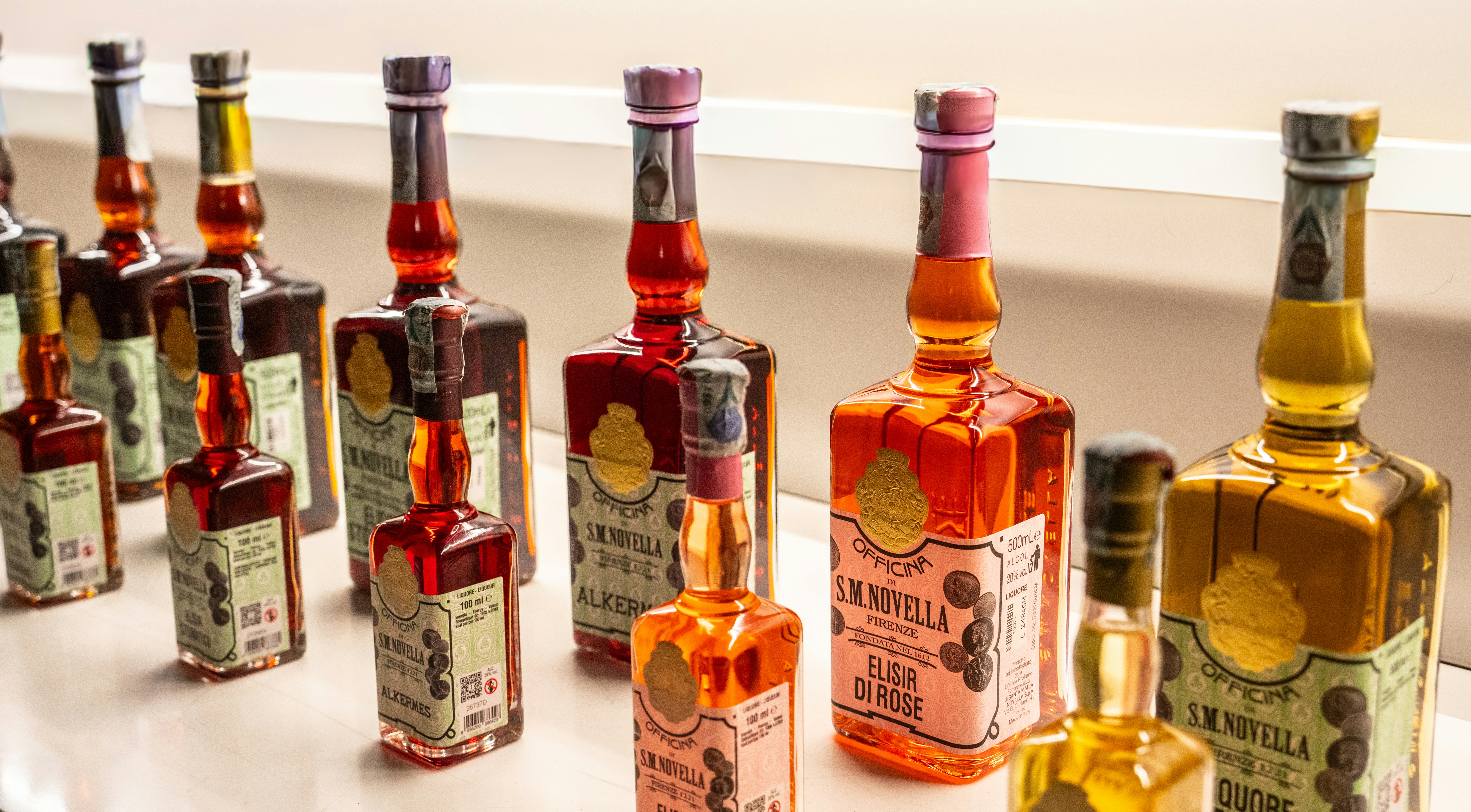Assortment of colorful liqueur bottles on a shelf.
