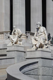 Two marble statues of men sitting on steps
