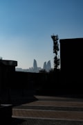 Baku Flame Towers illuminated at night above the old walled city with the Caspian Sea in the background