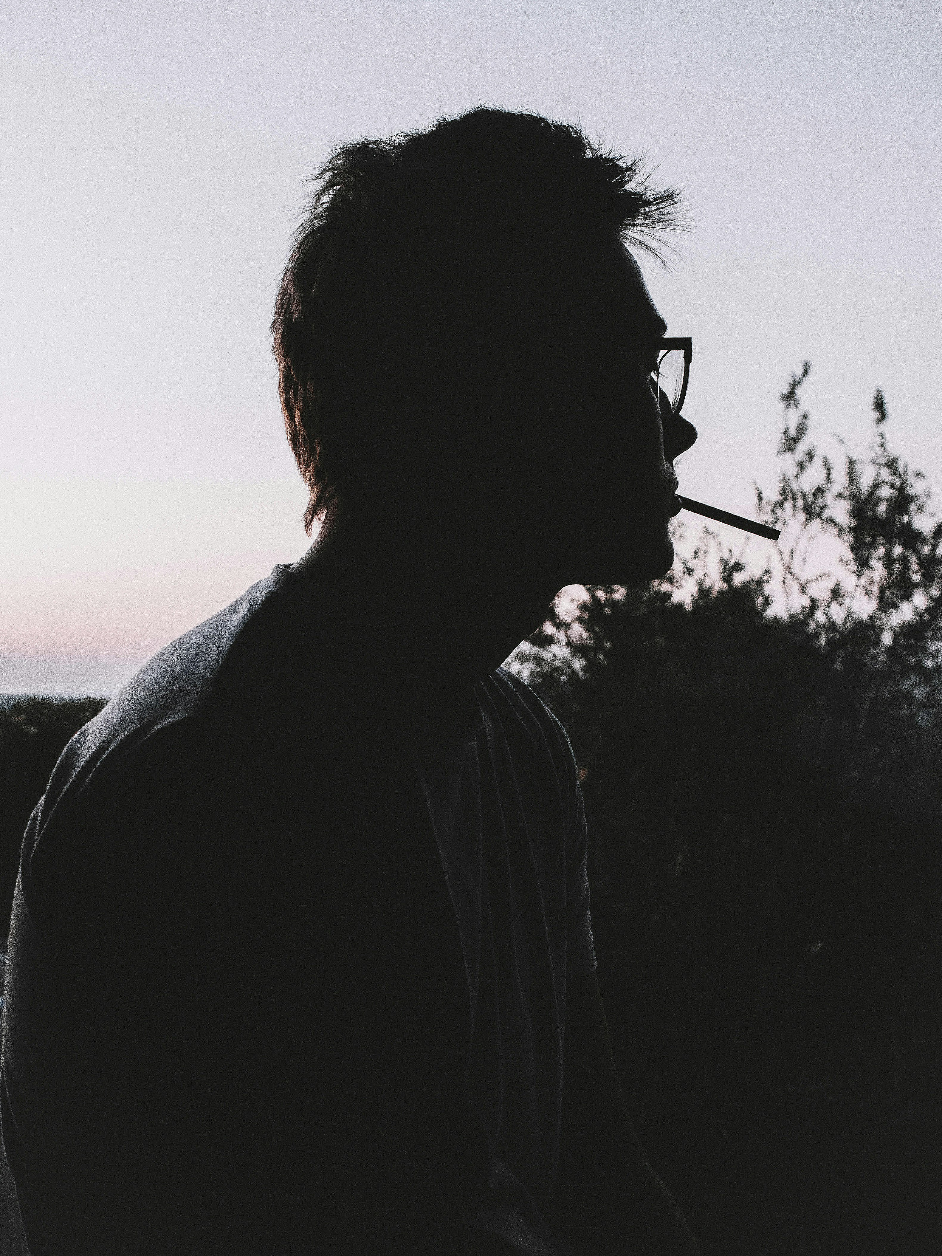 Silhouette of a man smoking outdoors at dusk